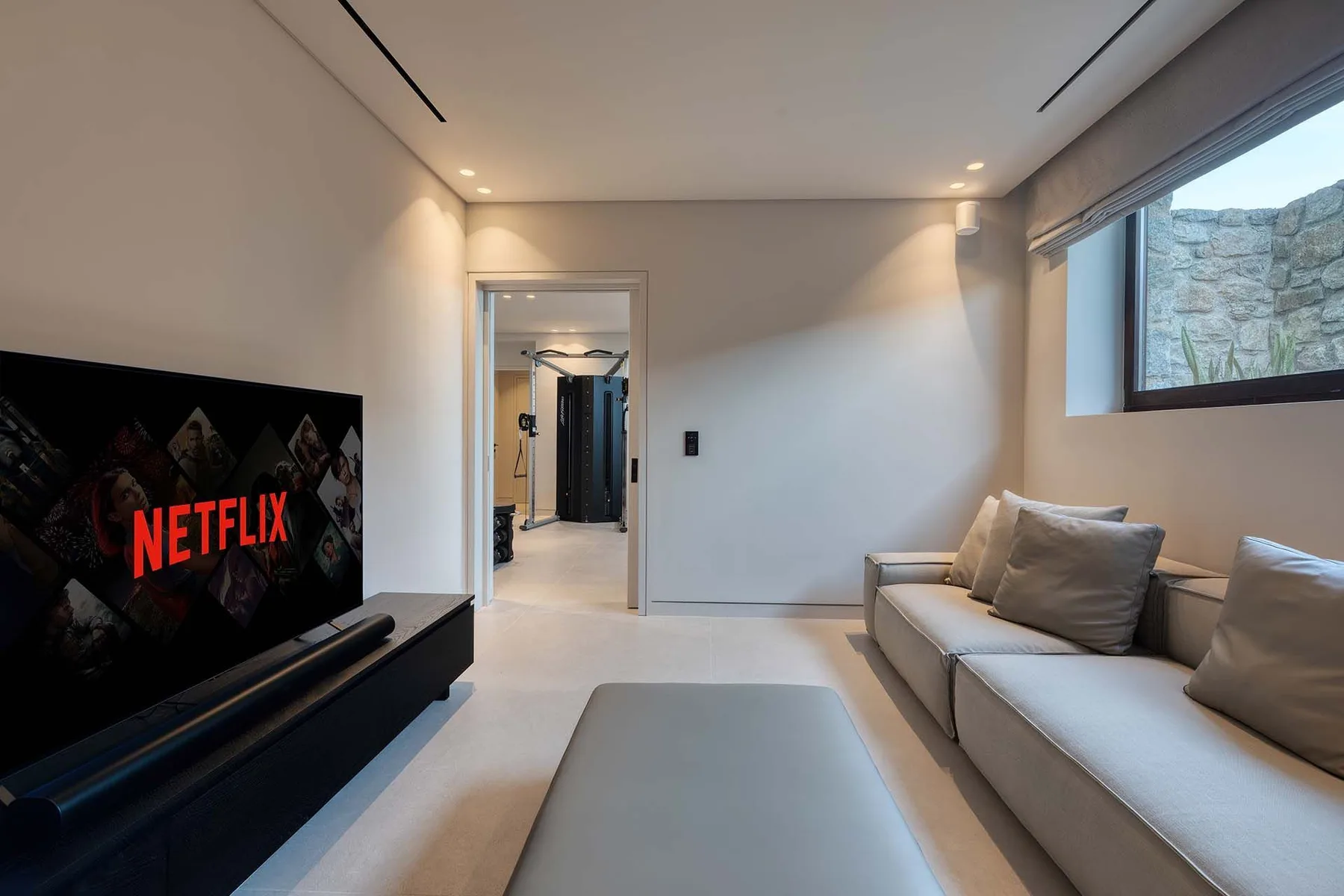 A modern living room with a television, seating, and a large window.