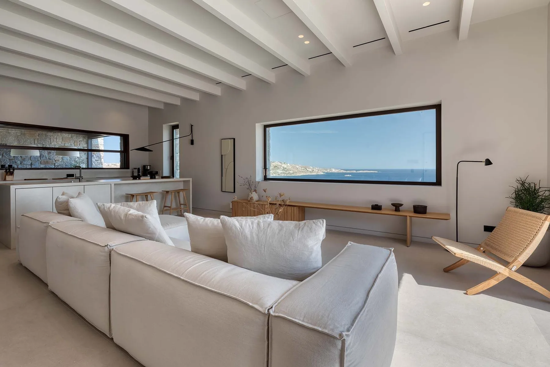 A bright living room with a large white sectional facing a wide picture window.
