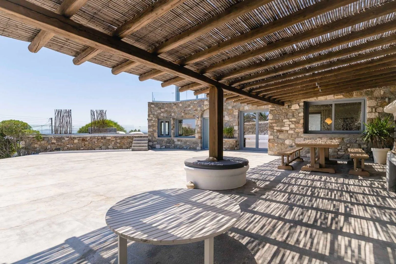 A stone terrace with a shaded seating area and open views of the sky.