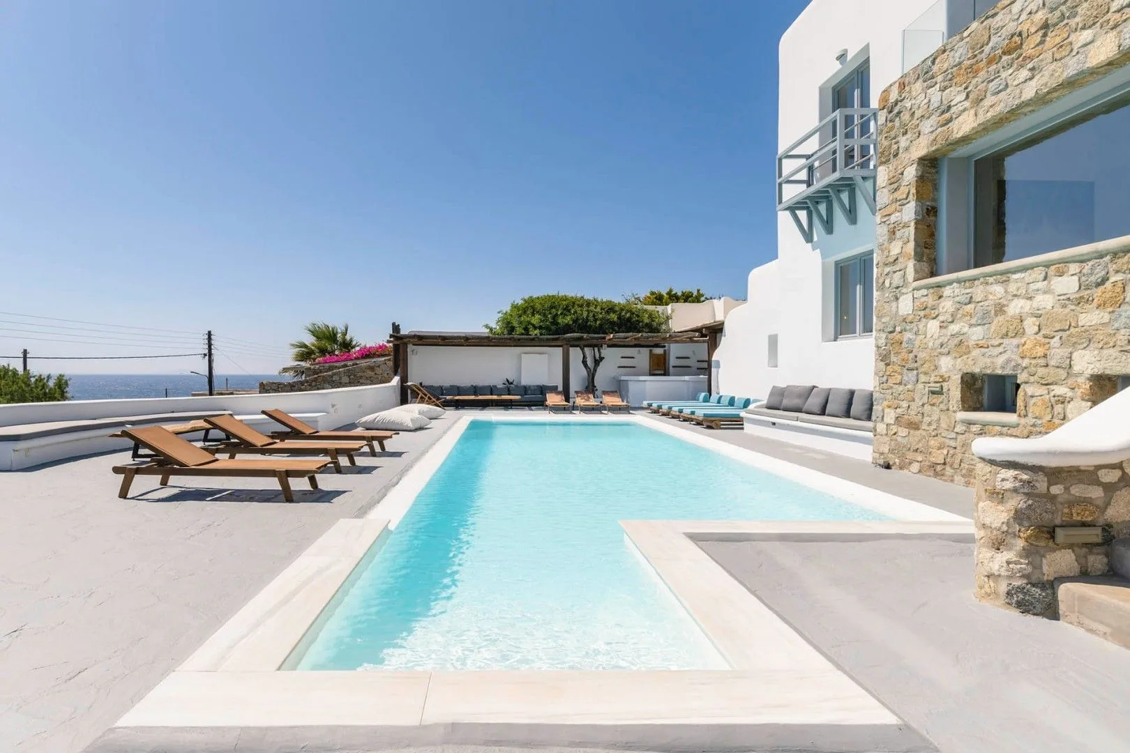 An outdoor swimming pool beside a stone-faced building, with lounge seating.