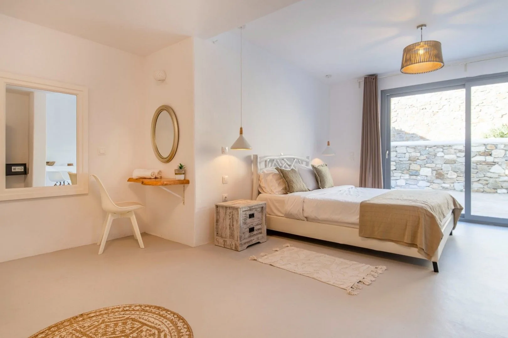 A bright bedroom with a bed, bedside table, and large glass doors.