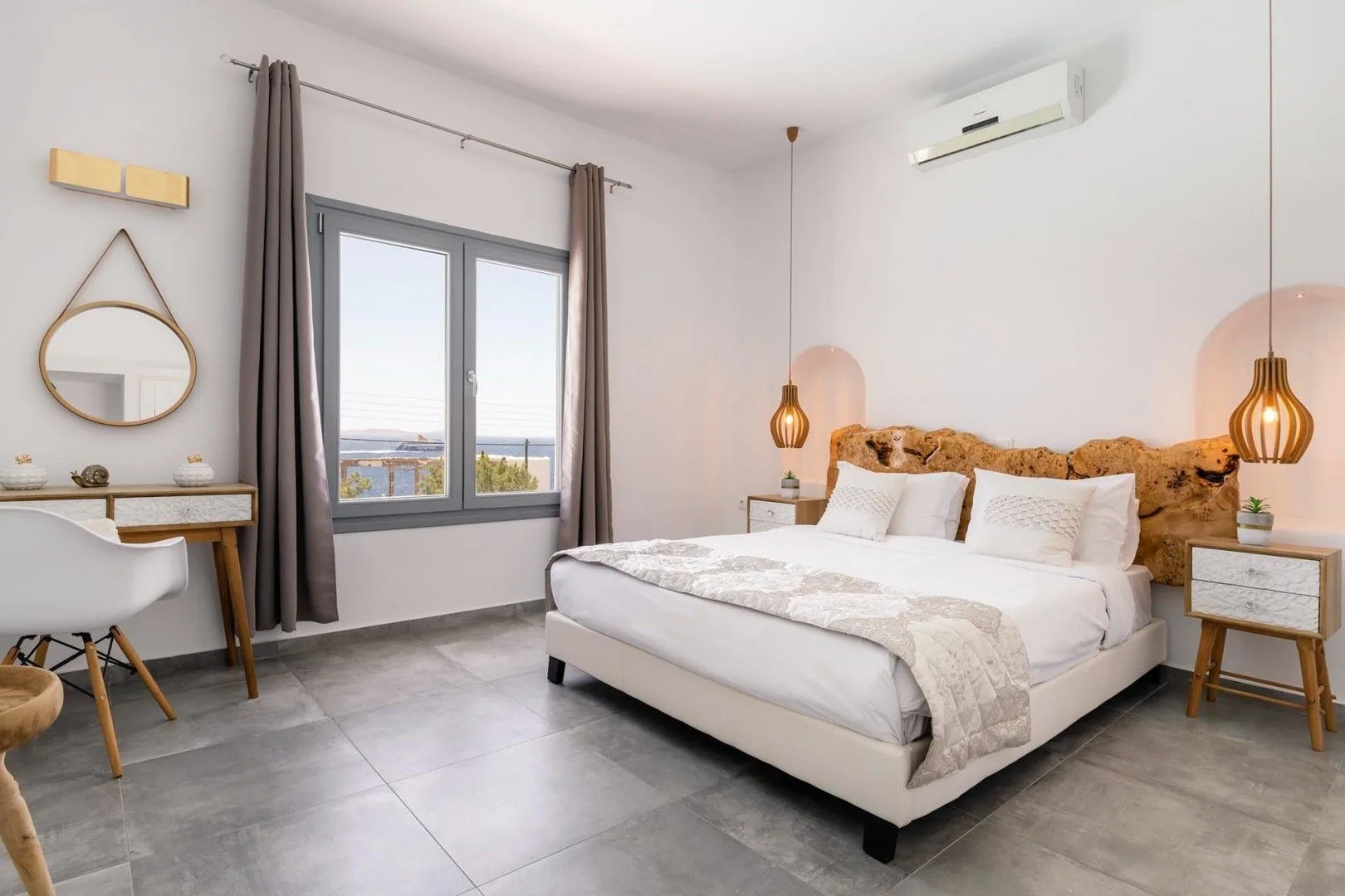 A bright bedroom with a bed, bedside tables, and a large window.