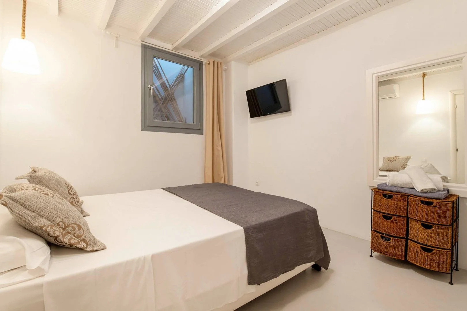 A bedroom with a bed, a wall-mounted television, and a dresser.
