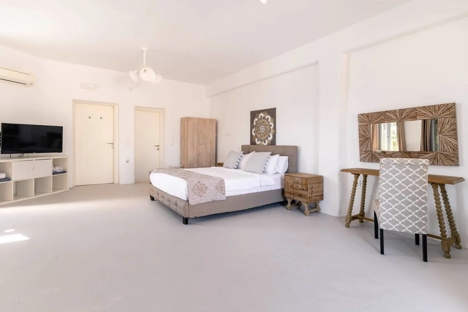 A bright bedroom with a bed, television, and small dining table.