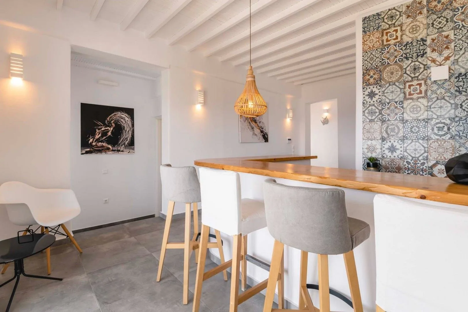 A bright dining area with a long wooden table and patterned tile wall.