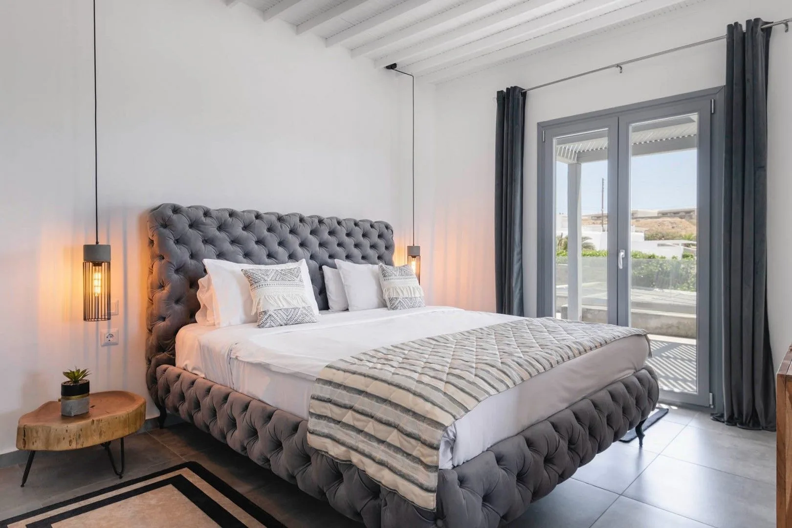A bright bedroom with a large bed and glass doors opening onto a balcony.