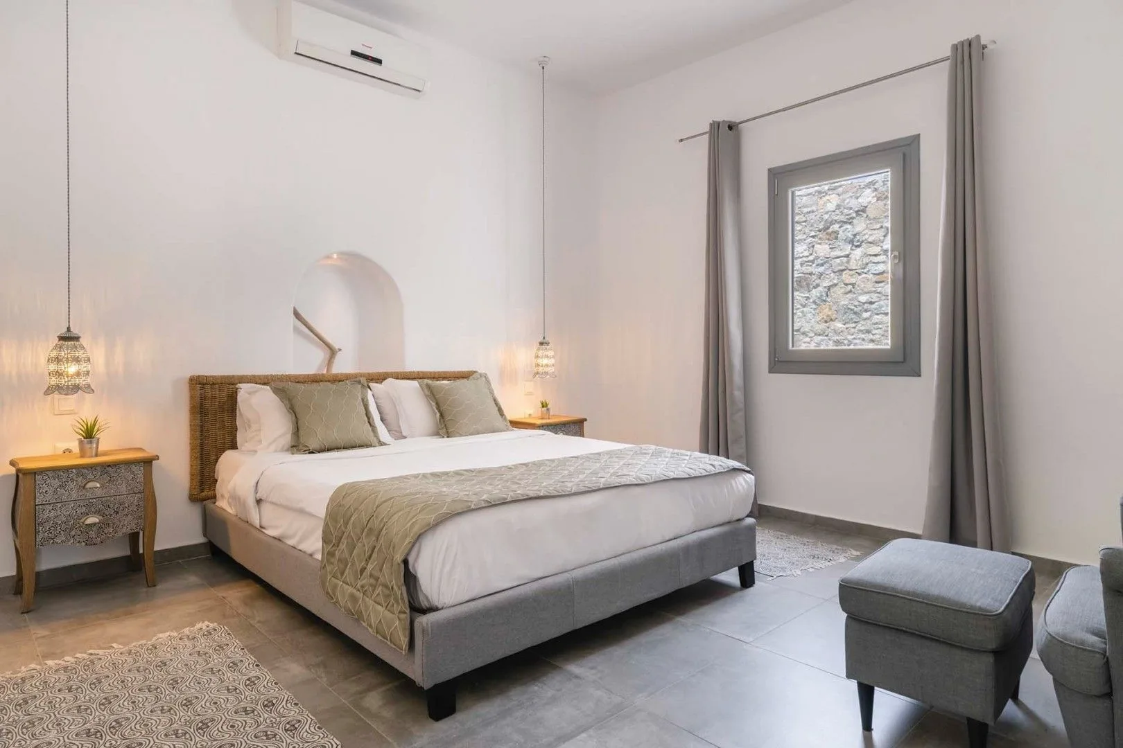 A bedroom with a bed, bedside tables, and a curtained window.