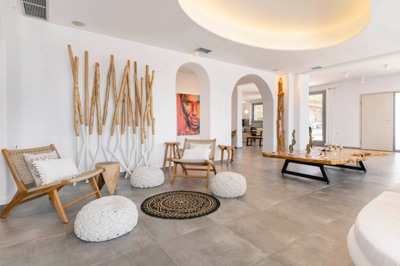 A bright lounge with seating, woven floor cushions, and a low table.