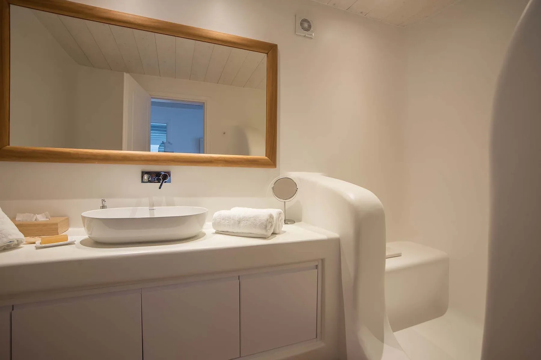 A bathroom vanity with a sink, mirror, and a toilet beside it.