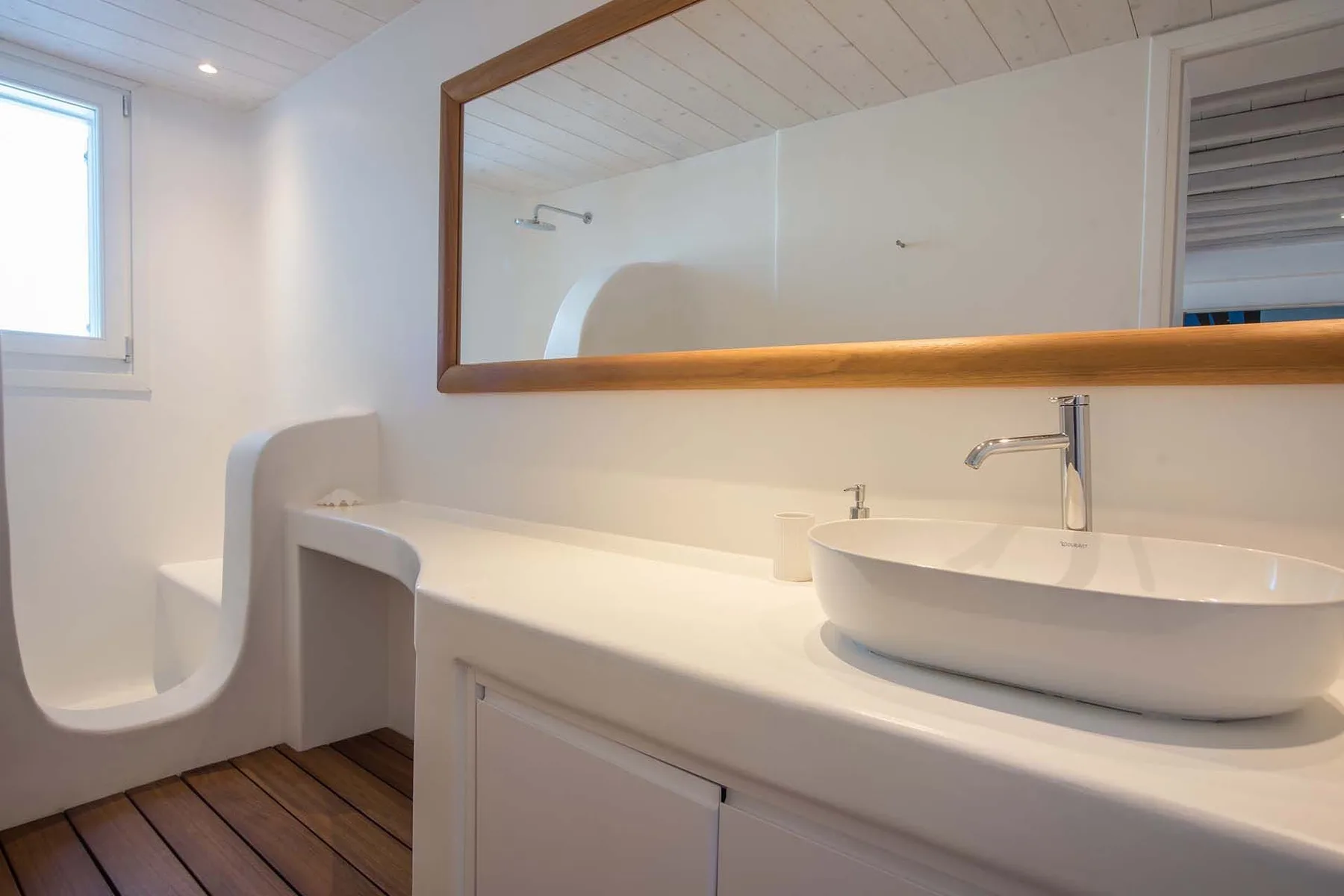 A bright bathroom with a long vanity, vessel sink, and large wall mirror.