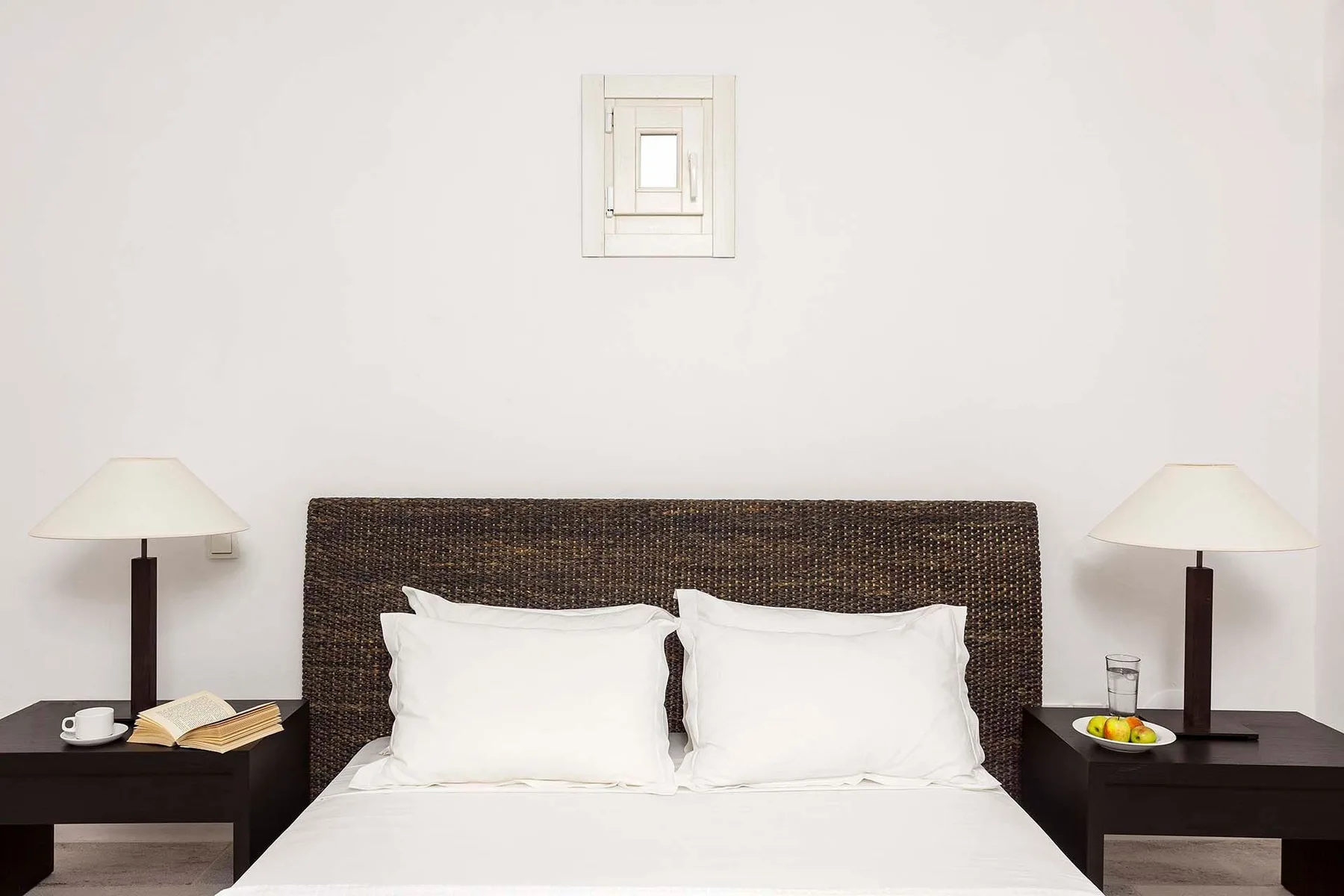 A bedroom with a bed, dark headboard, and matching bedside lamps.