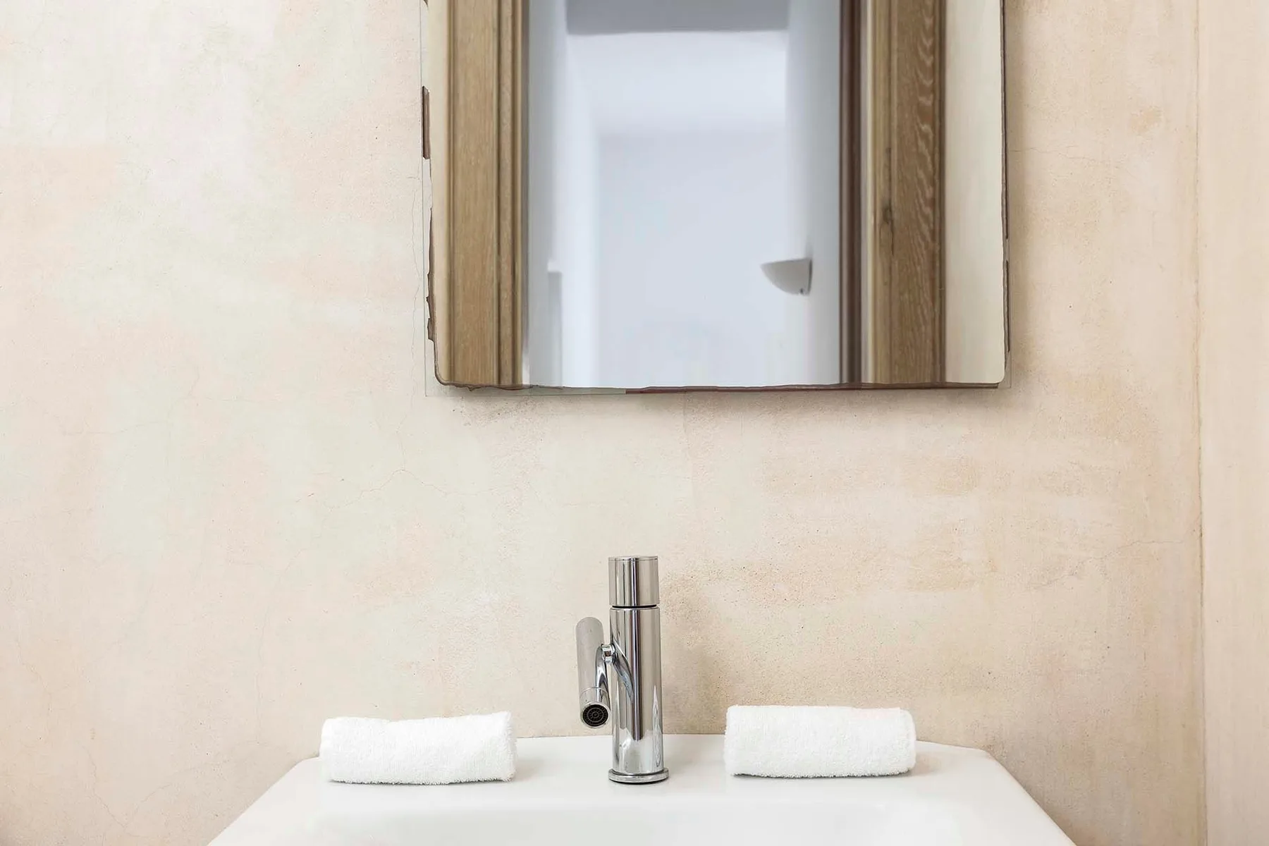 A bathroom vanity with a wall mirror and two folded towels.