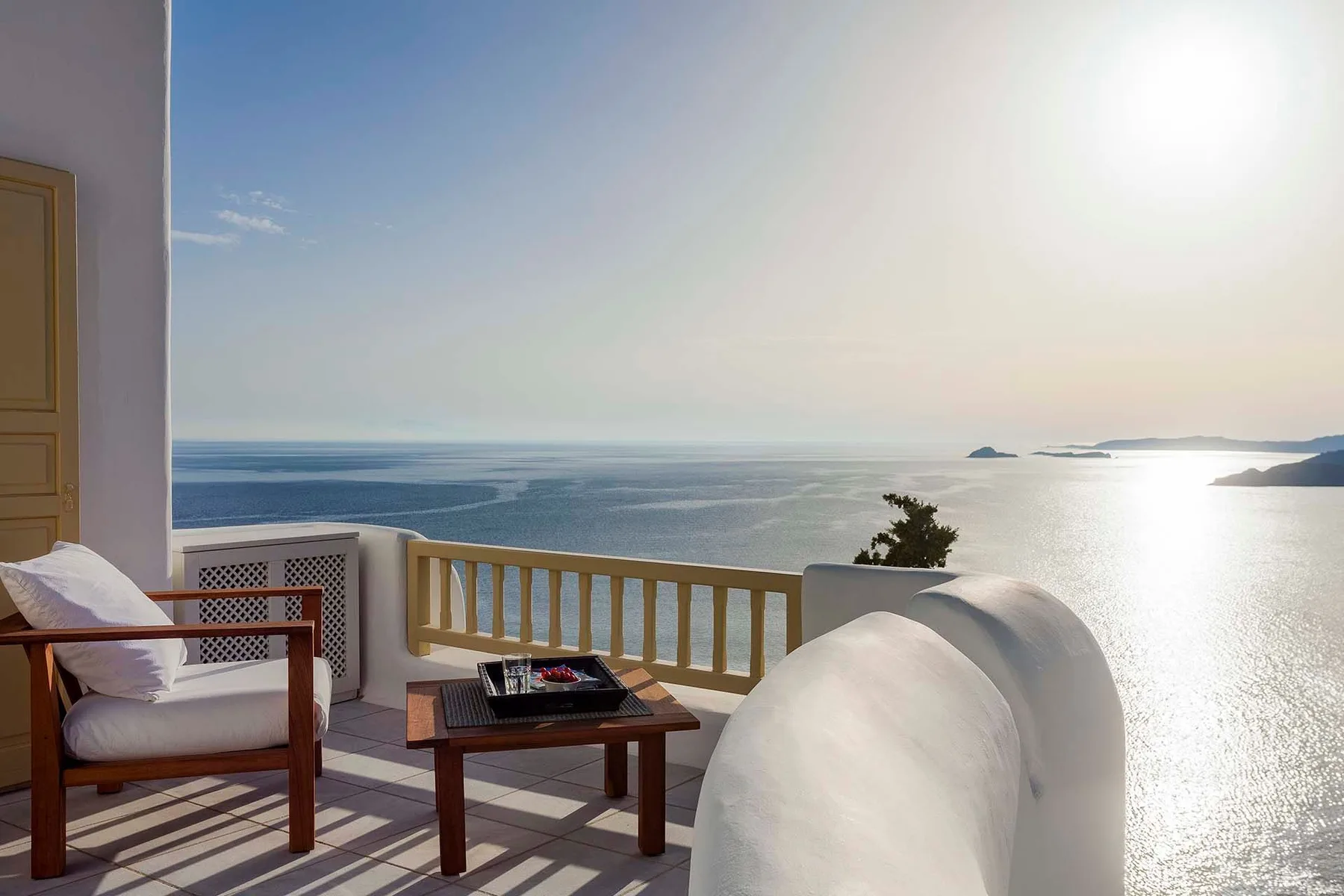 A seaside balcony overlooks the water, with outdoor seating and a small table.