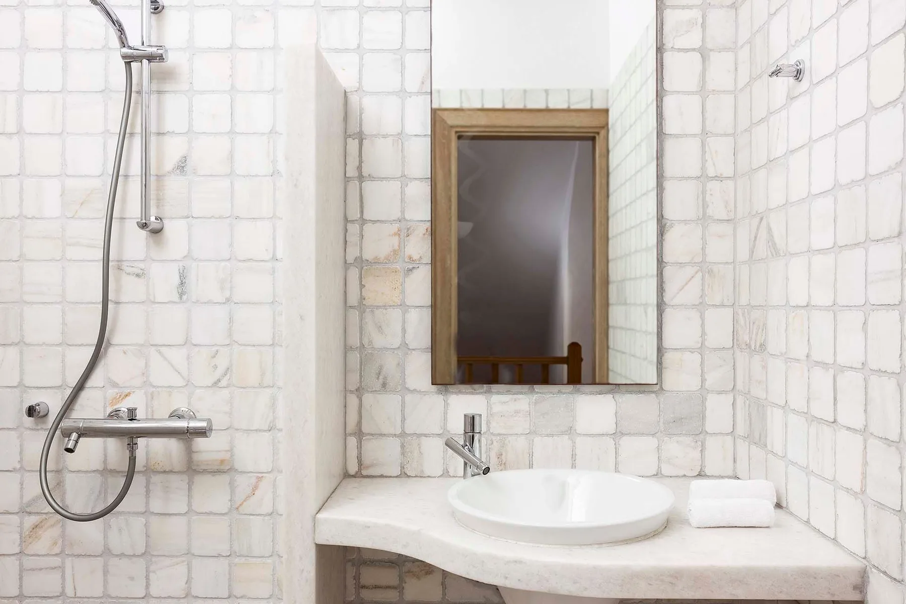 A tiled bathroom with a shower, sink, and wall mirror.