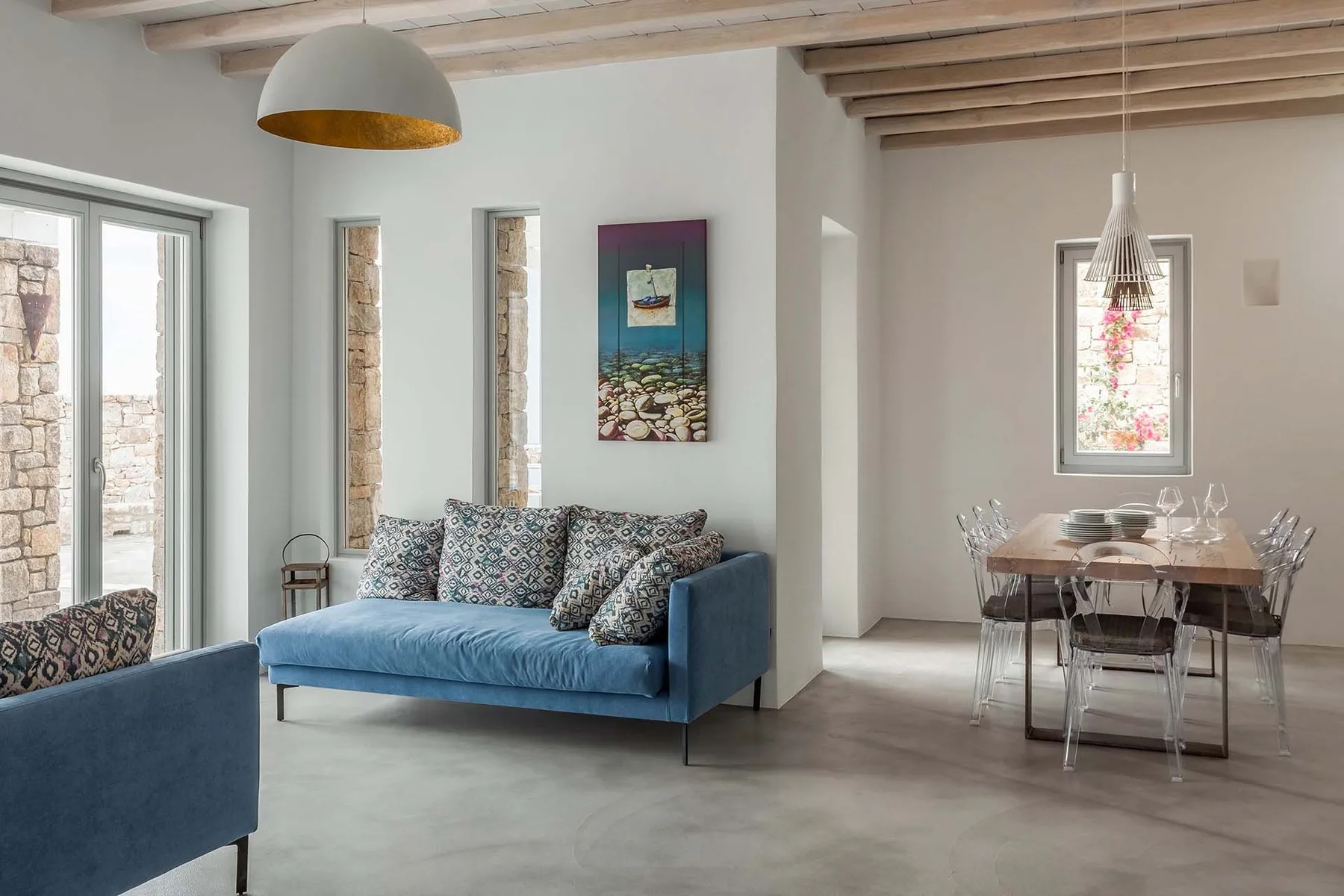 A bright living and dining area with blue seating and a dining table.