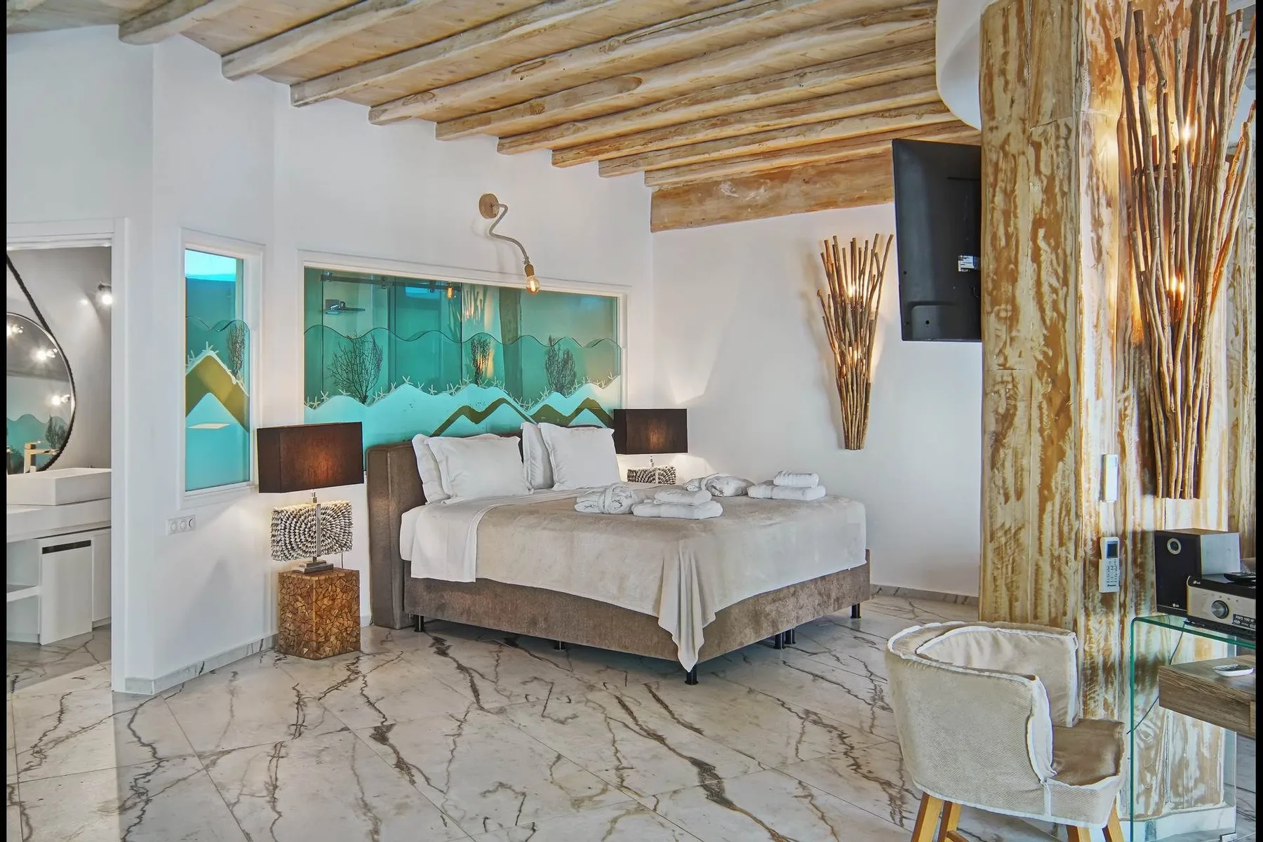 A bedroom with a large bed, turquoise wall panels, and exposed wooden ceiling beams.