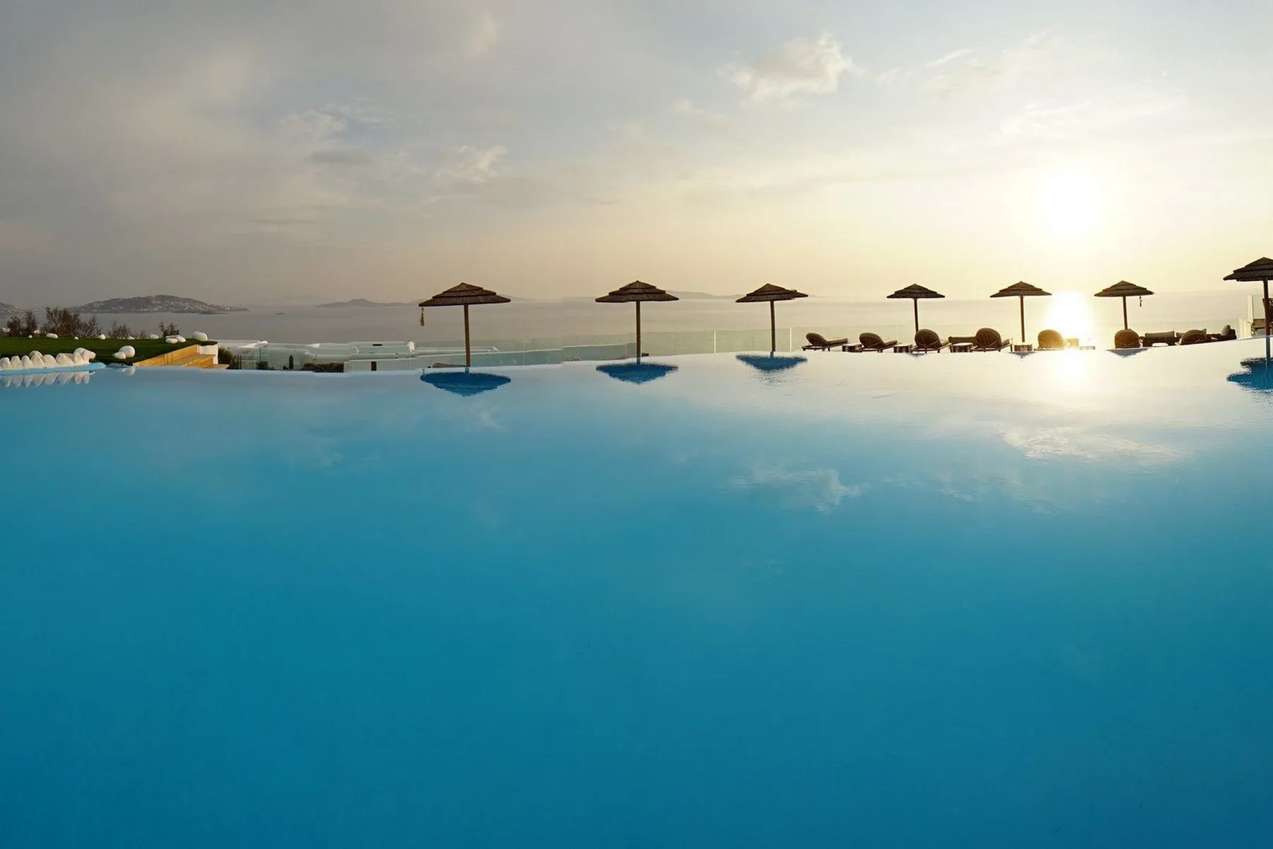 An infinity pool overlooks the sea, with parasols along the far edge.