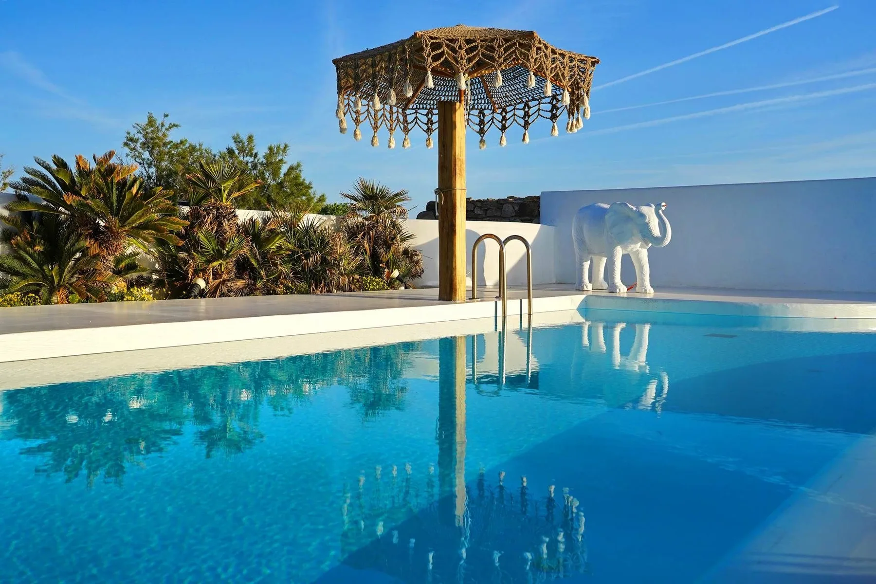 An outdoor swimming pool with a decorative canopy and an elephant statue.