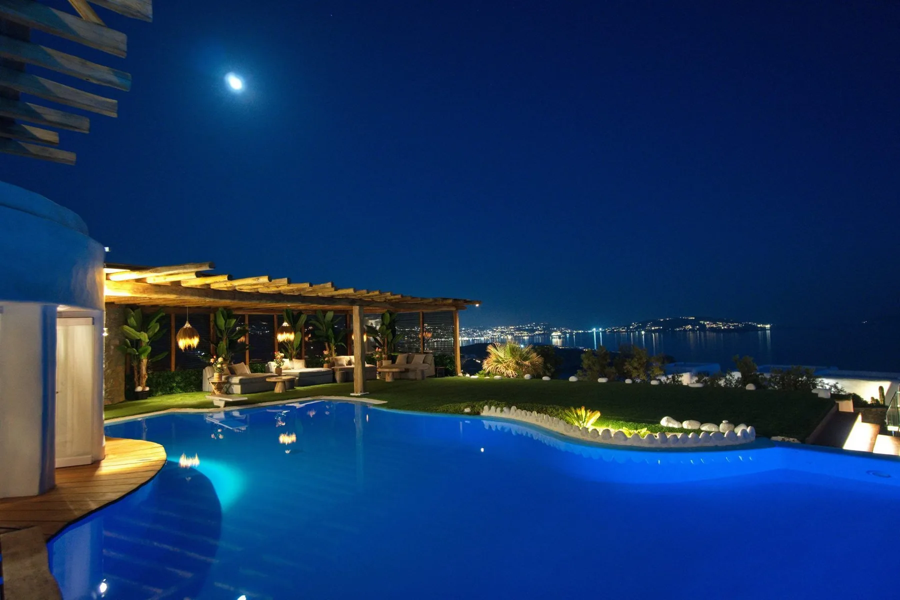 A swimming pool at night overlooks a distant city skyline.