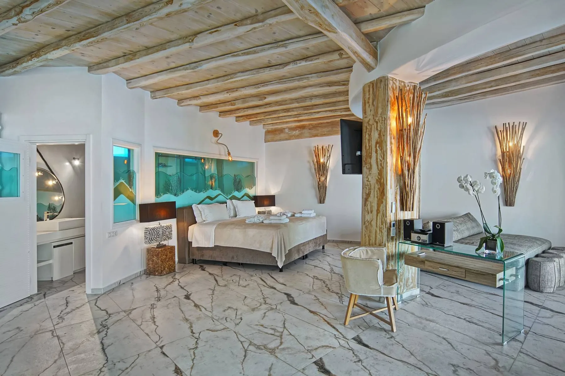 A bedroom with a bed, seating area, and decorative branch arrangements.