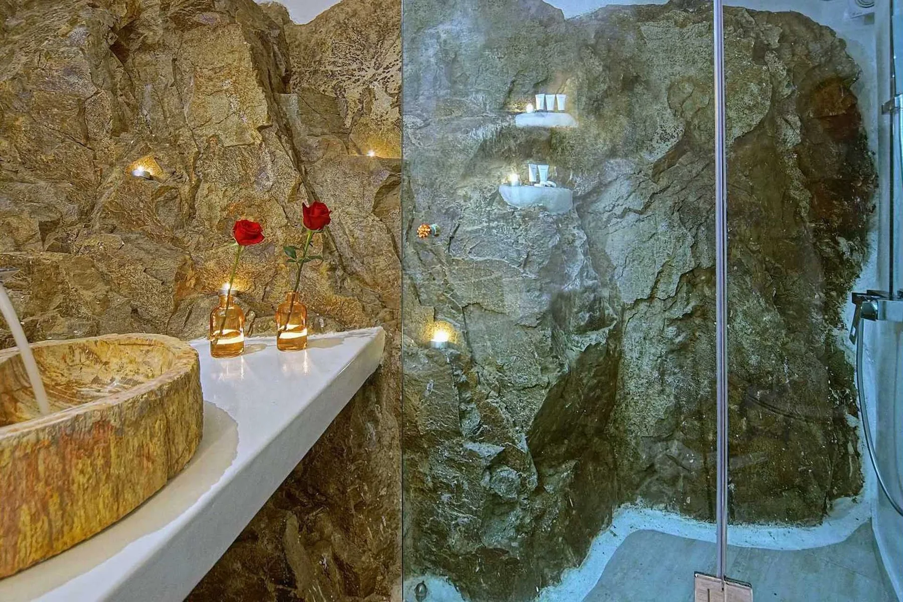 A stone bathroom with a bathtub, vanity, and glass-enclosed shower.