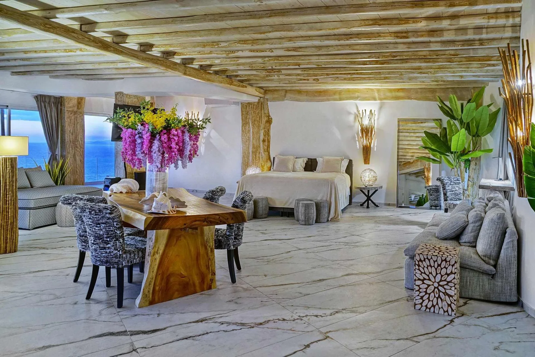 A spacious living area with a dining table, seating, and a bed.