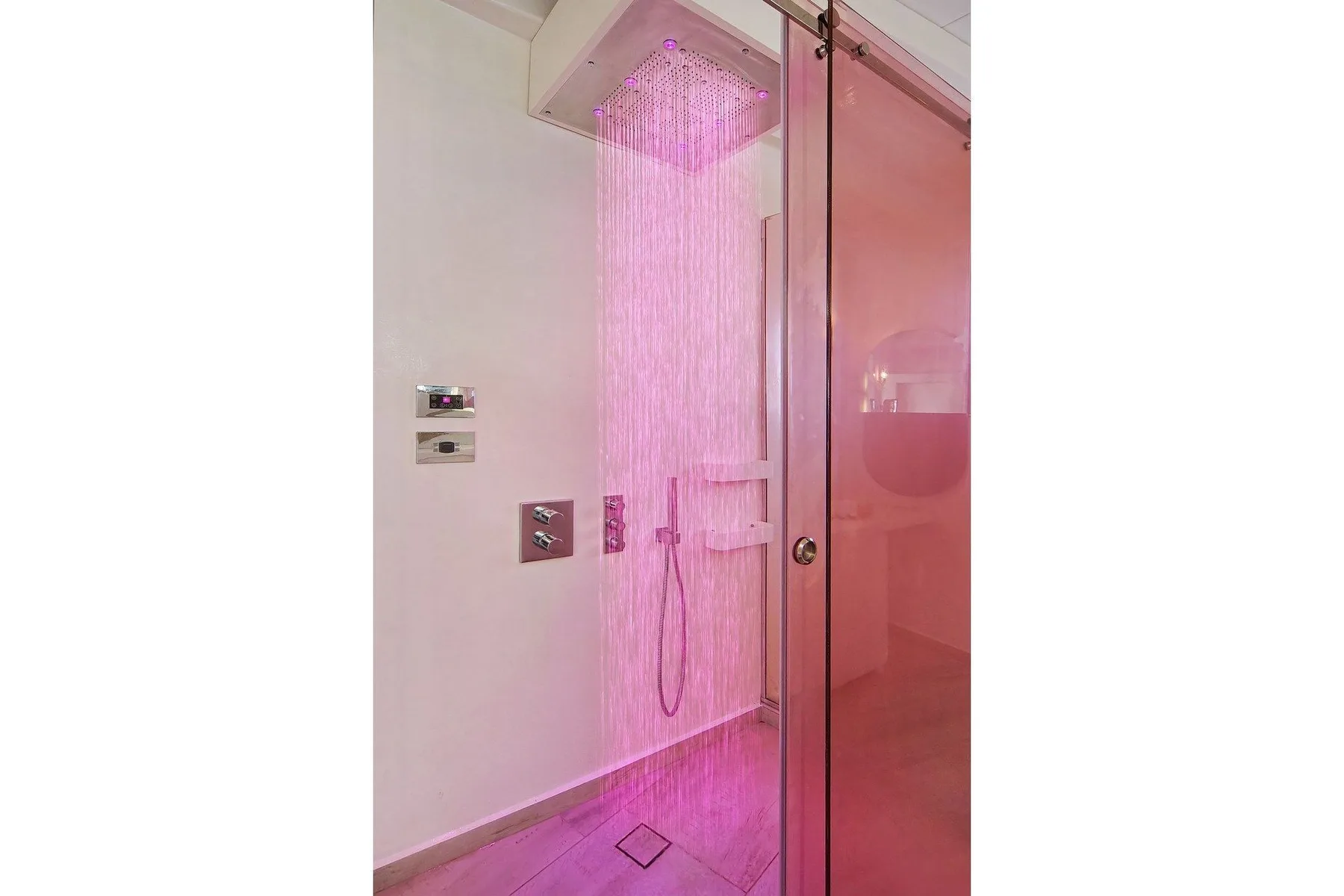 A modern shower area with pink lighting and a glass partition.