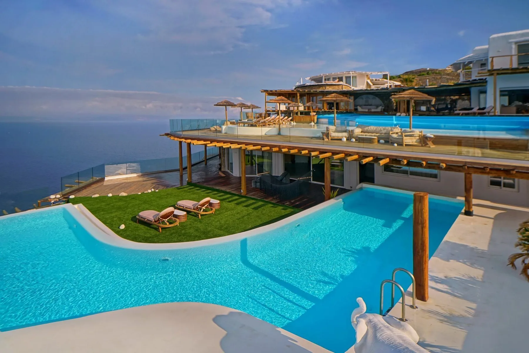 A seaside resort pool area with a raised terrace and lounge seating.