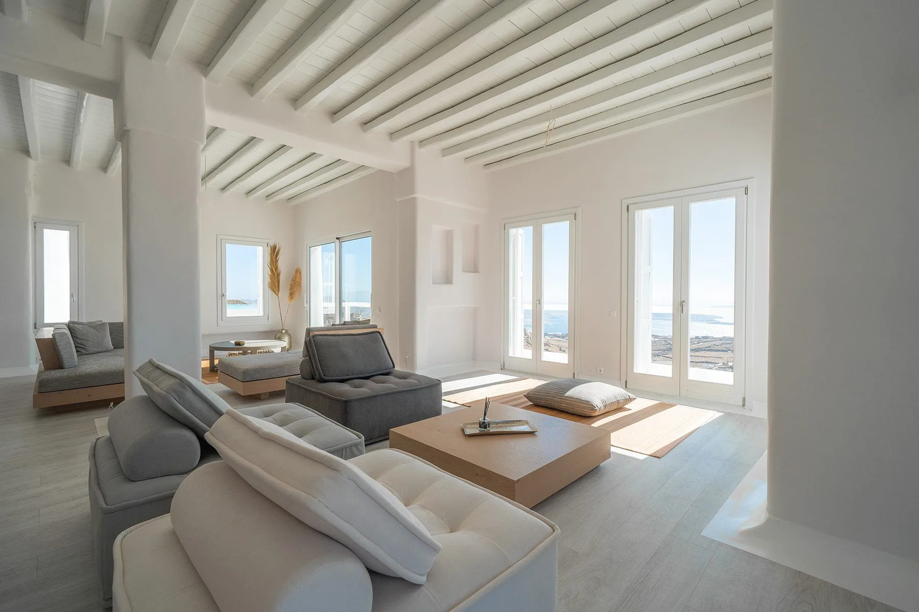 A bright living room with seating and large windows overlooking the water.