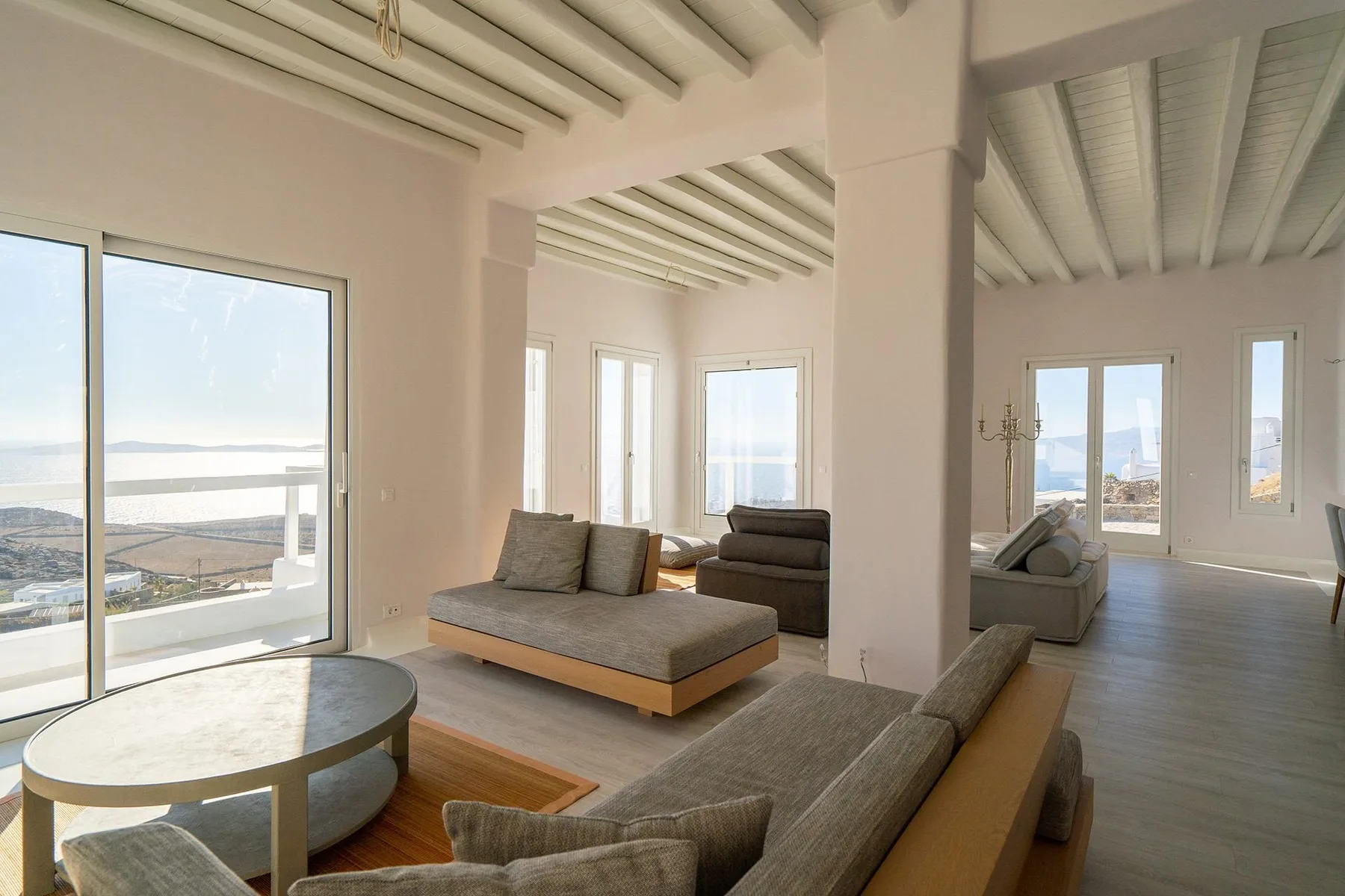 A bright living room with seating and large windows overlooking the water.