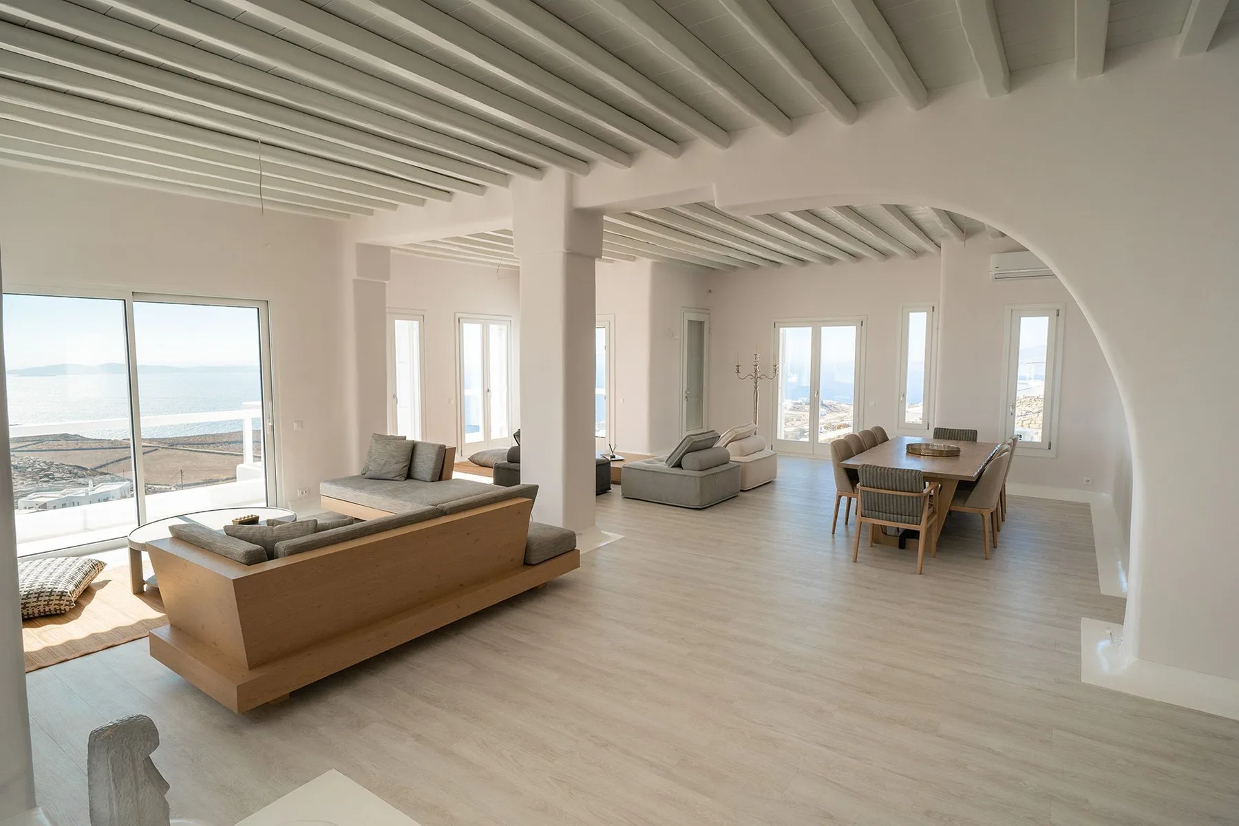 A bright open-plan living and dining area with seating beside large windows.