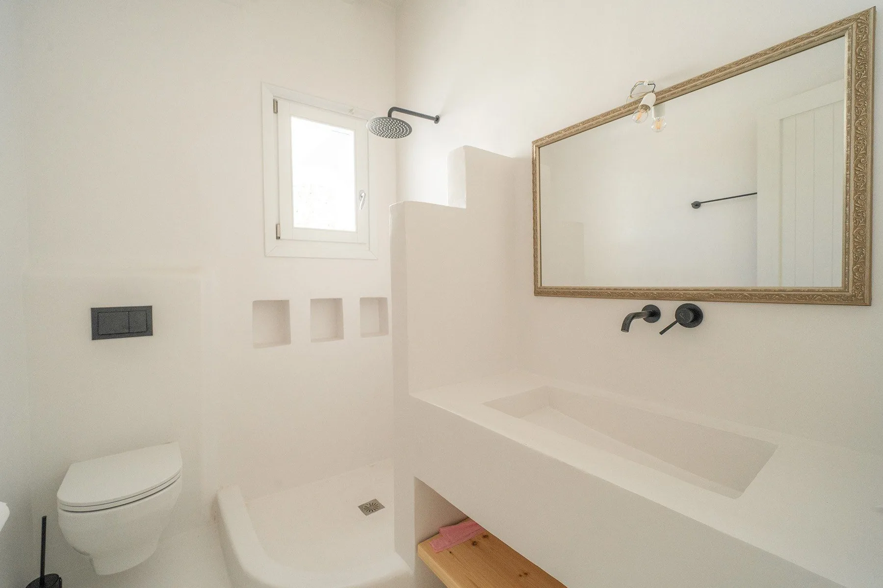 A bright bathroom with a shower, toilet, and large wall mirror.