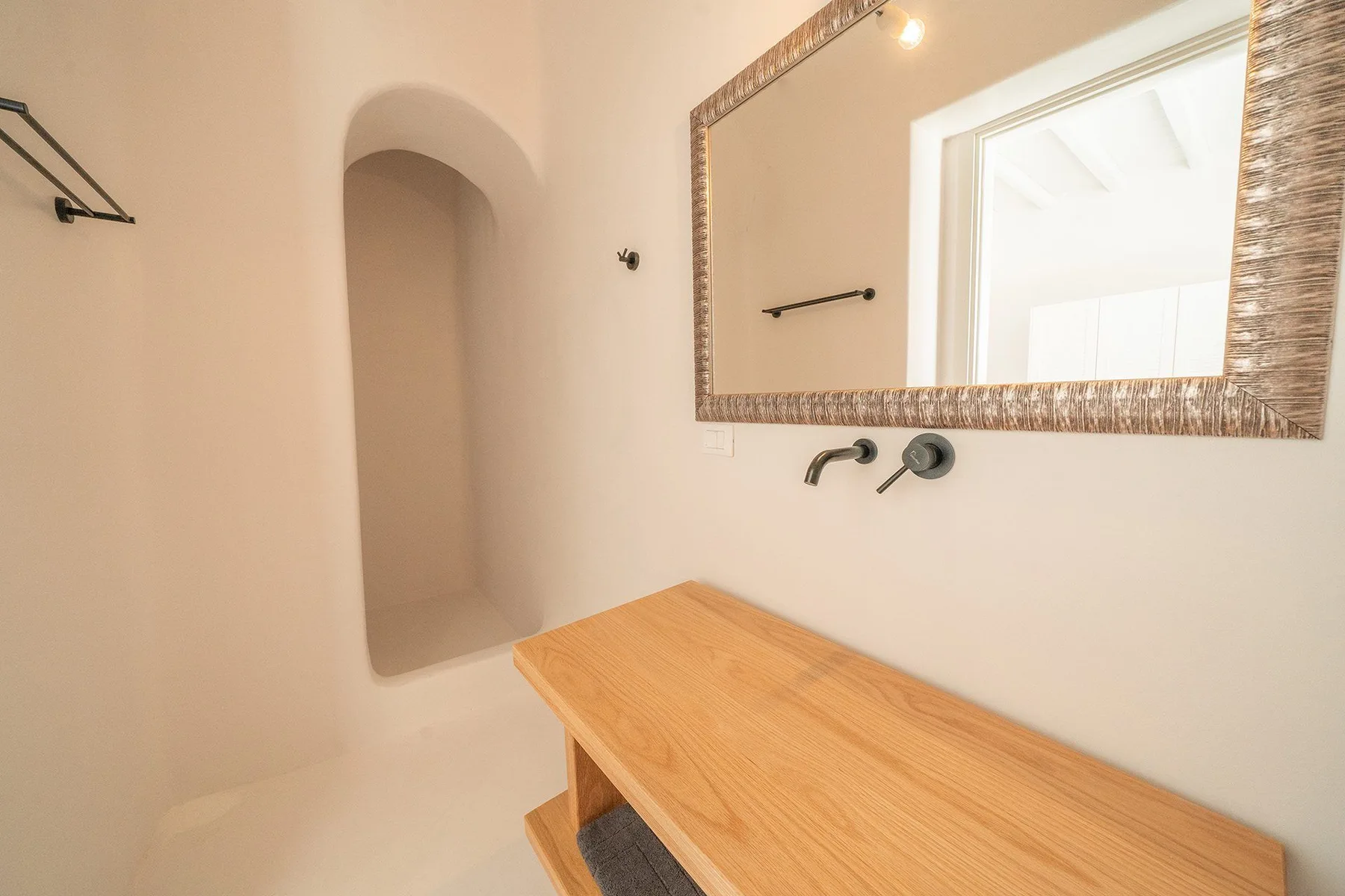 A bathroom vanity with a wooden countertop sits beneath a large wall mirror.