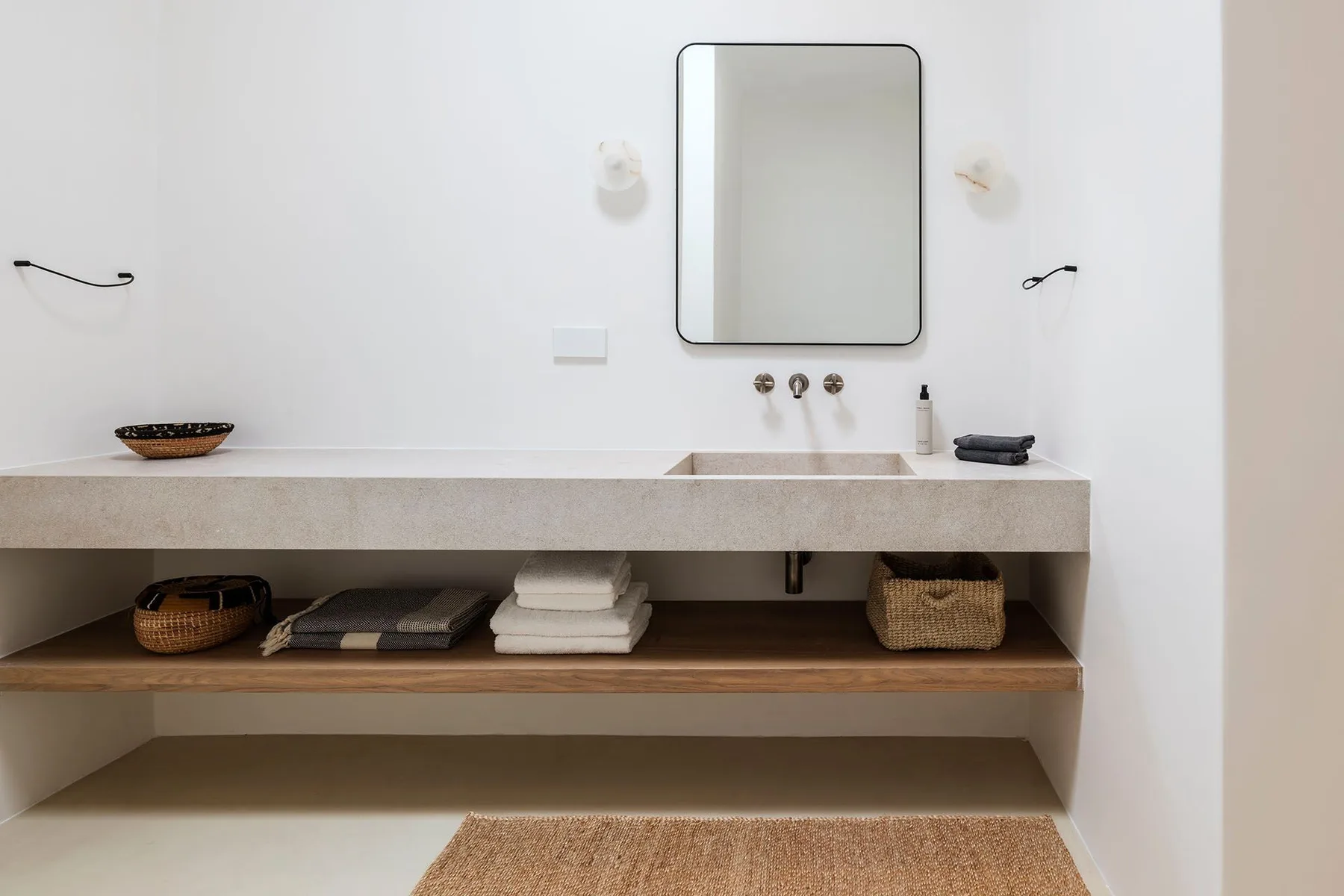 A bathroom vanity with a rectangular mirror and open storage shelves.