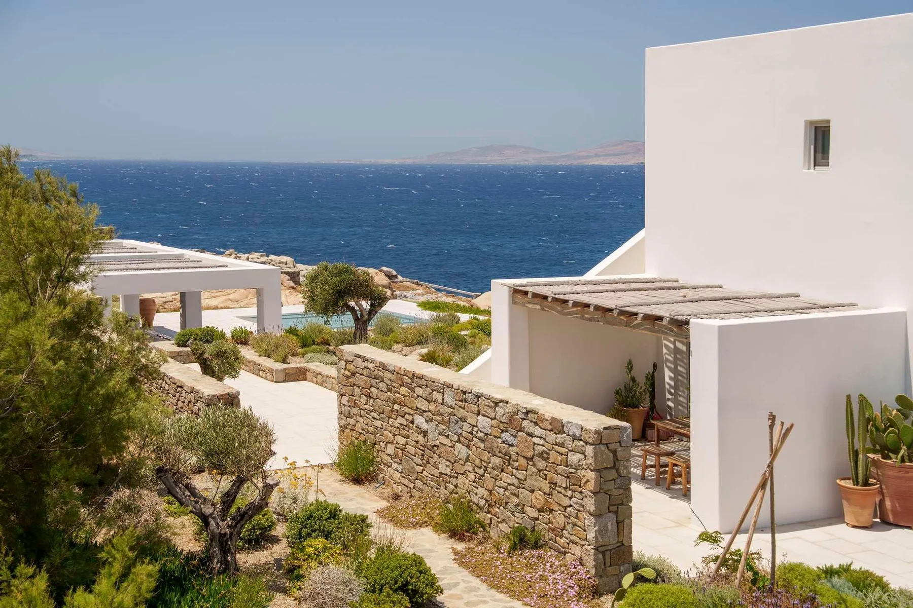 White buildings and stone walls overlook the sea in a coastal scene.