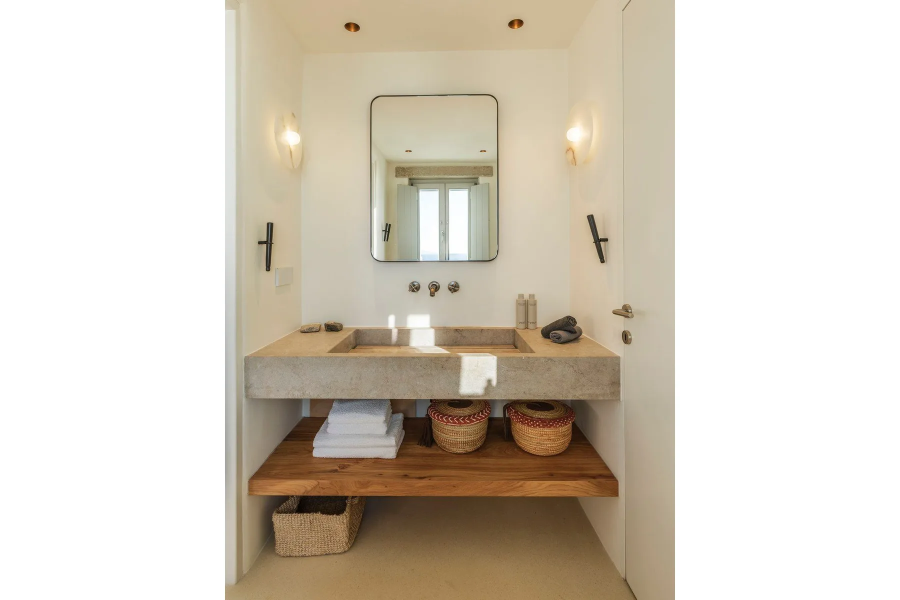 A bathroom vanity with a wall mirror and open wooden shelves.