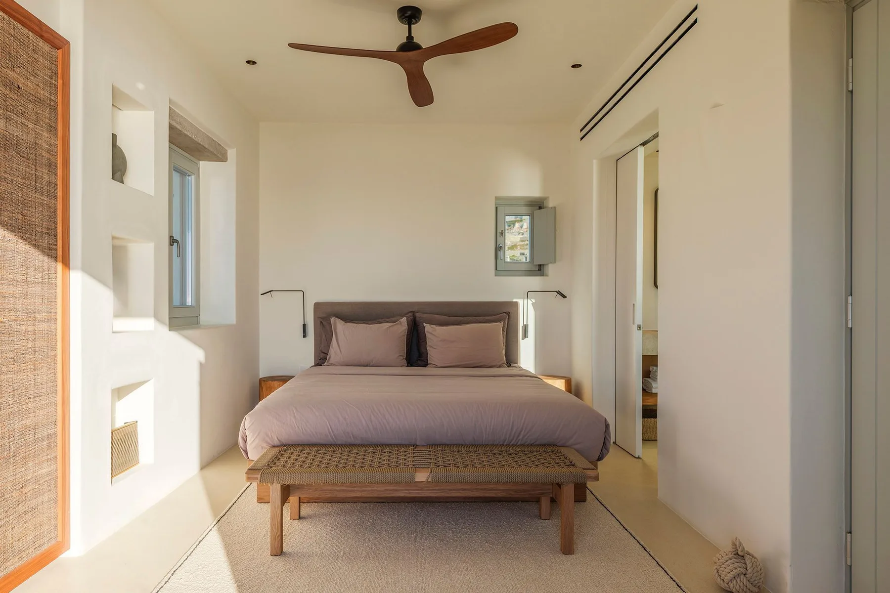 A bedroom with a neatly made bed beneath a ceiling fan.