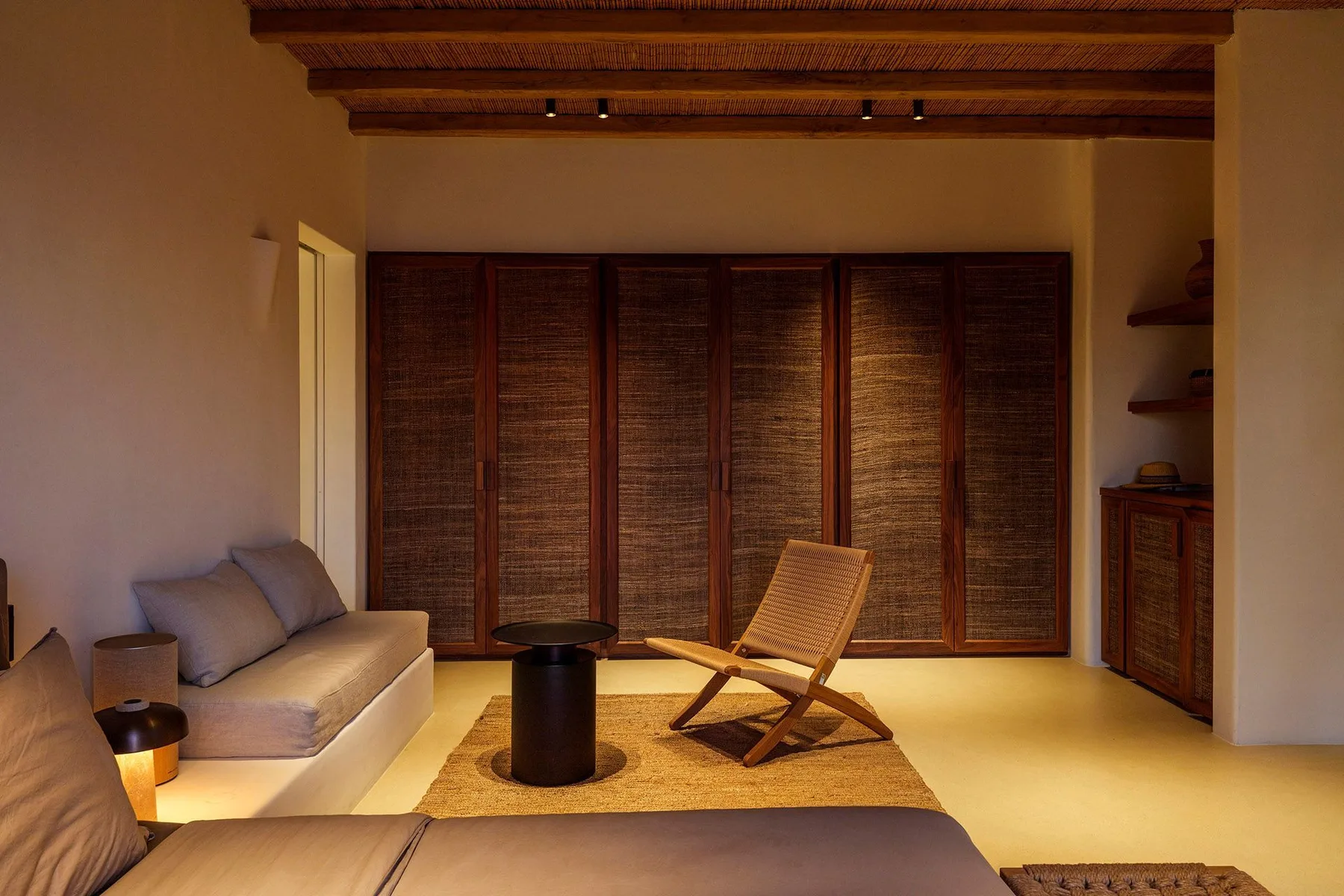 A warm living room with seating, a low table, and wooden screens.