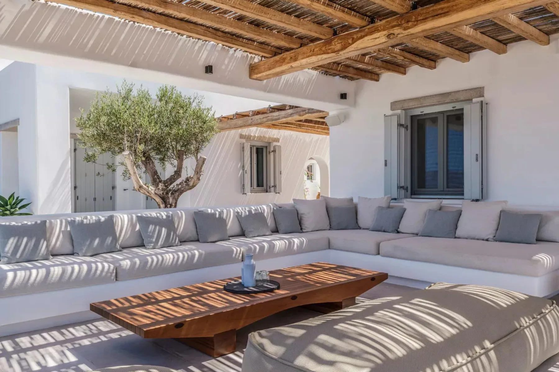 A bright outdoor lounge has built-in seating around a low wooden table.