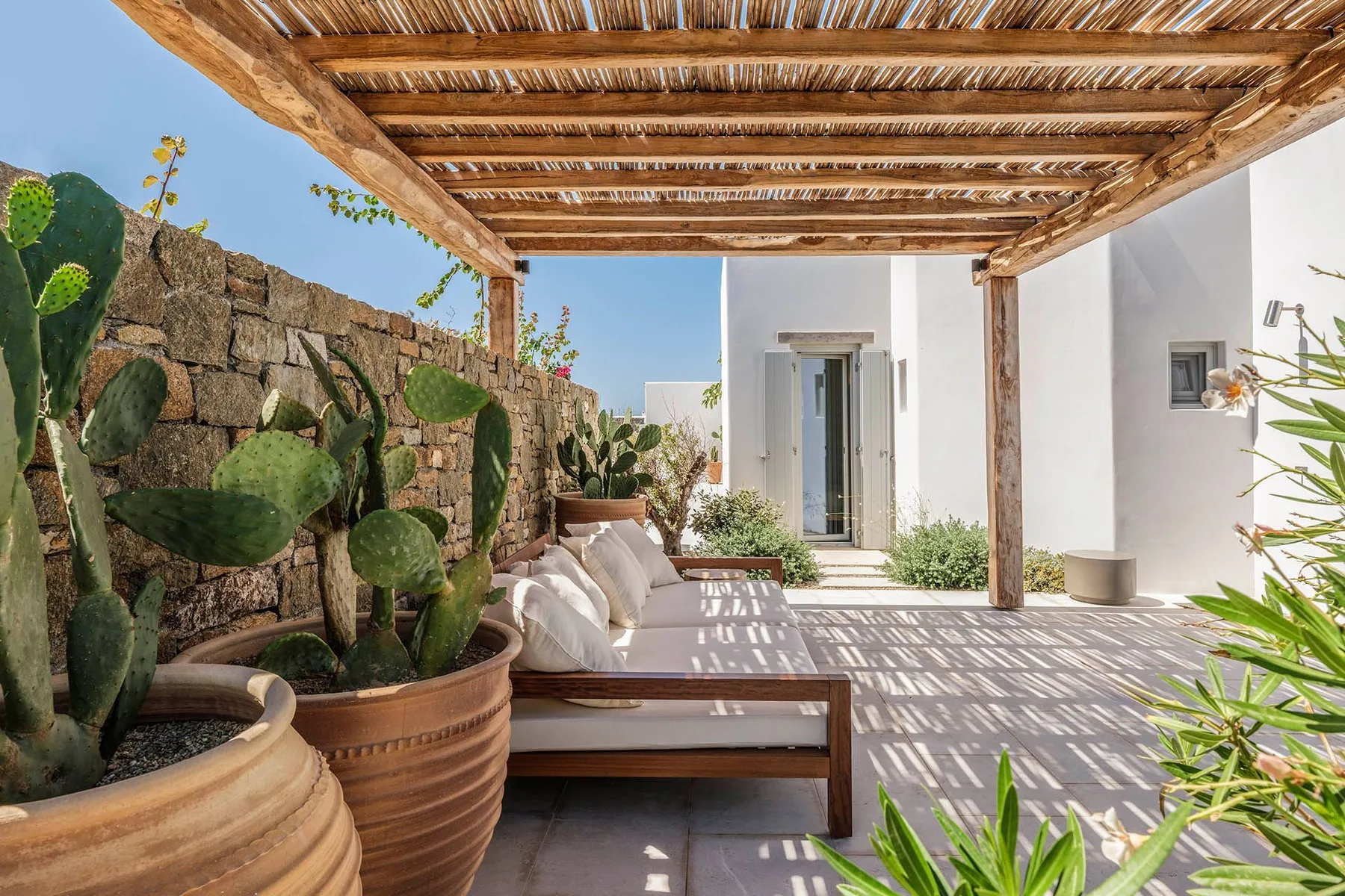 An outdoor patio with cushioned seating beneath a wooden pergola.