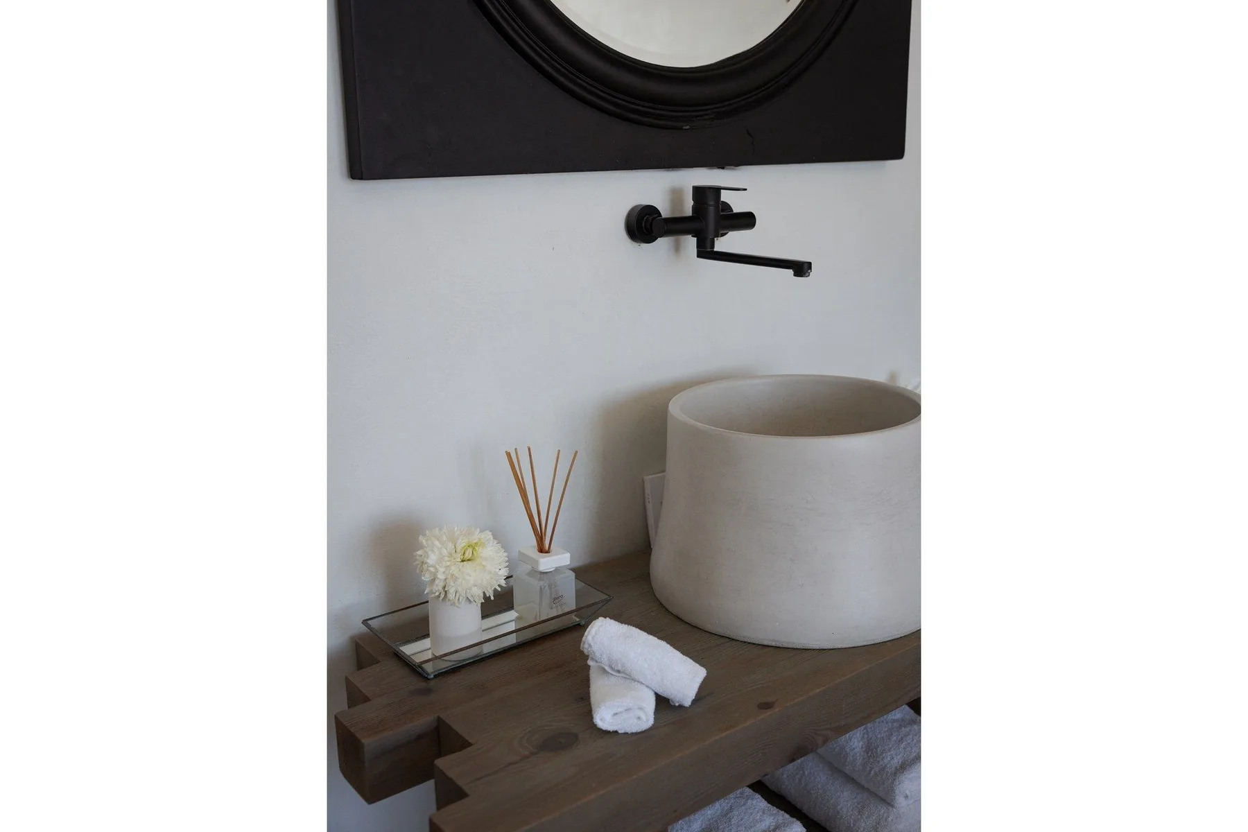 Un tocador de baño con lavabo sobre encimera, grifo de pared y espejo.