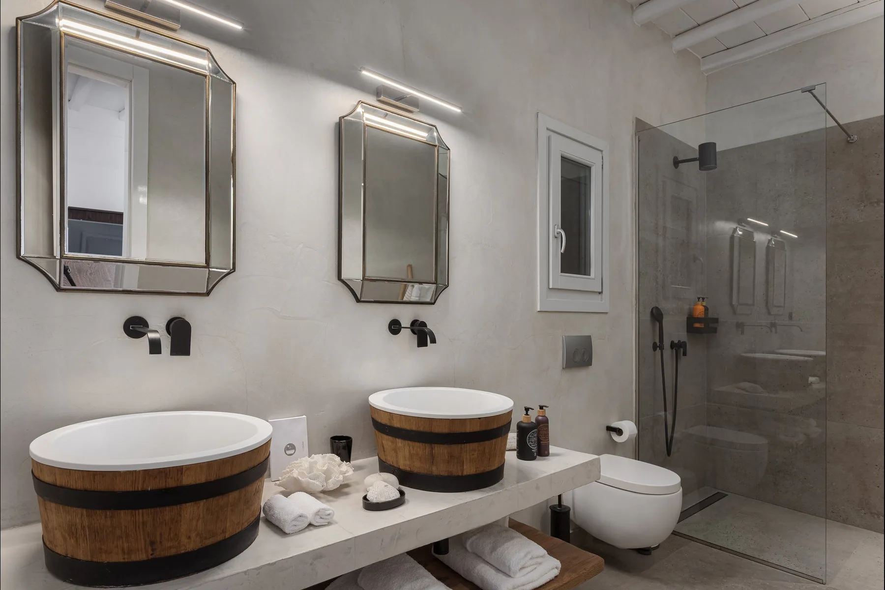 Un baño moderno con un tocador largo, dos lavabos sobre encimera y una ducha de vidrio.