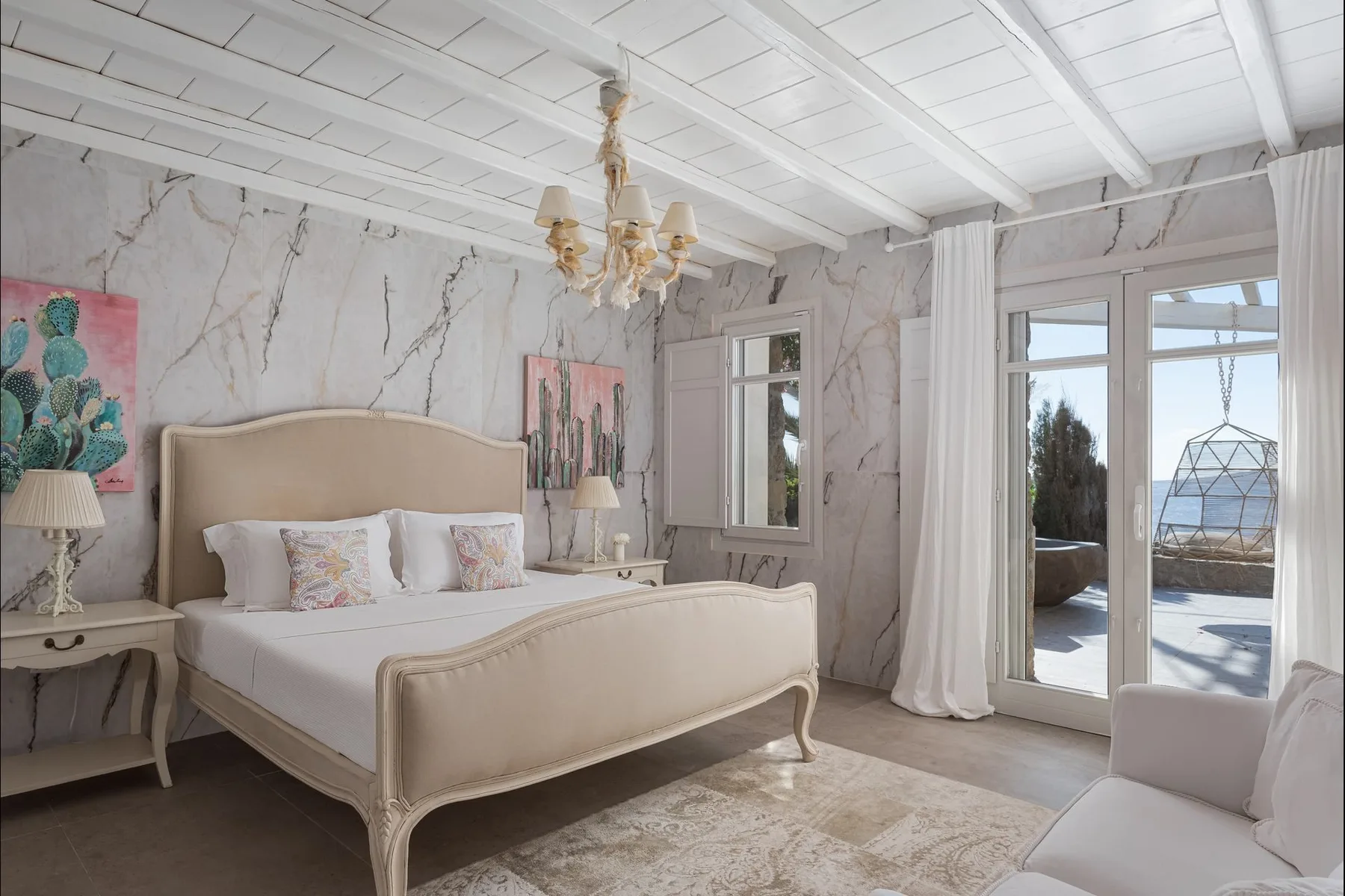 Un dormitorio con una cama, mesitas de noche y puertas de vidrio que dan a un patio.
