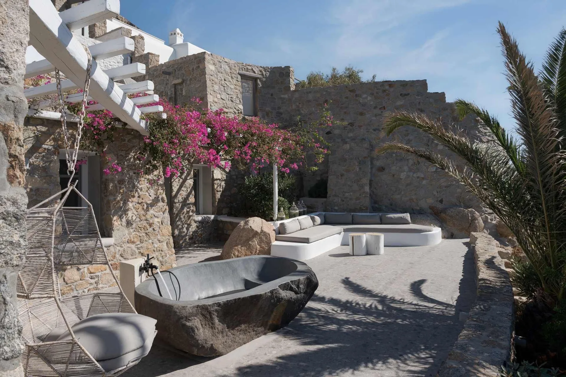 Un patio de piedra con una bañera exterior y asientos integrados.