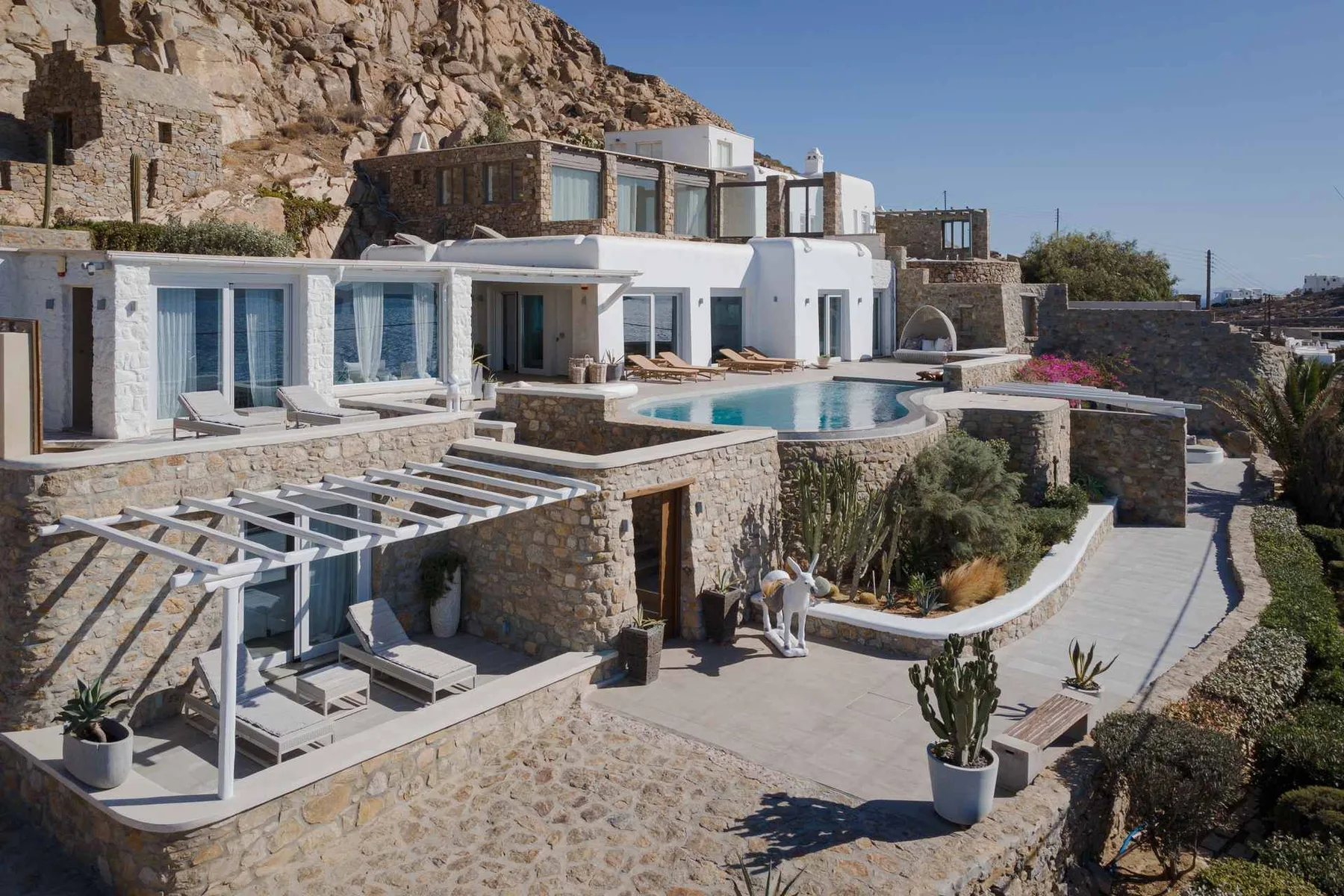 Un edificio blanco moderno con piscina y terrazas de piedra.