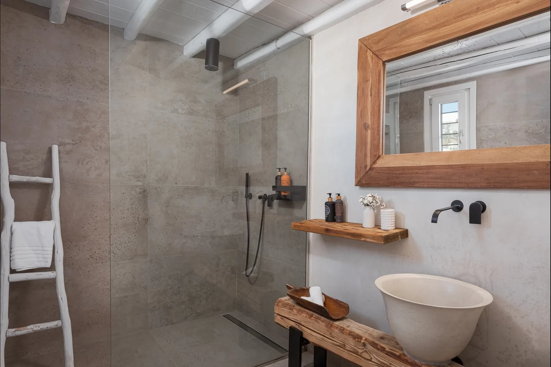 Un baño con ducha, lavabo sobre encimera y un gran espejo de pared.