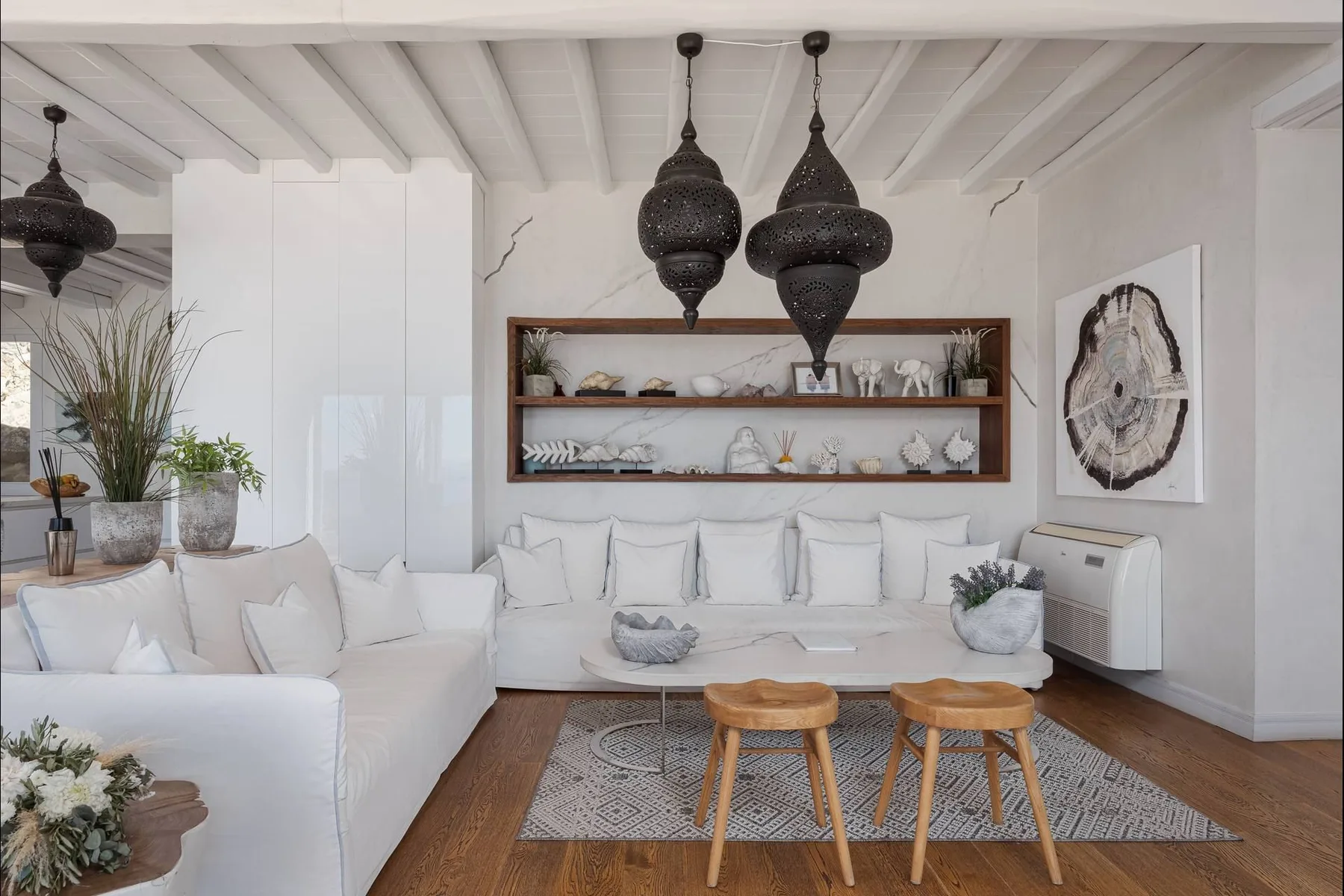 Una sala luminosa con asientos blancos, una mesa baja y estantes abiertos.