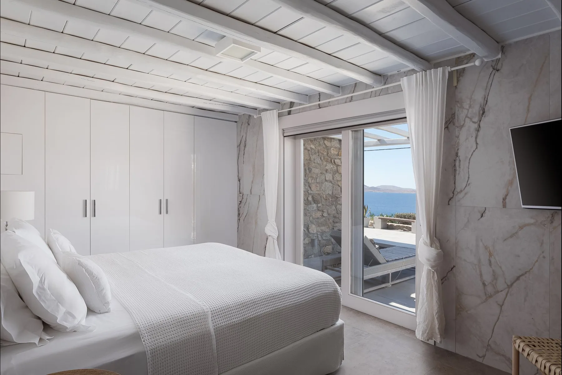 Un dormitorio con una cama junto a una puerta de vidrio que da a un balcón.