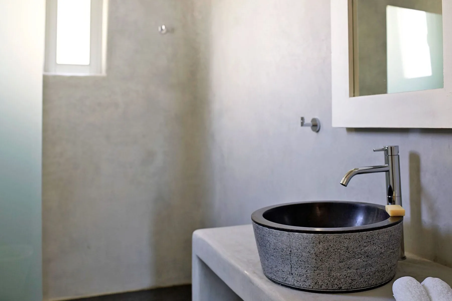 A bathroom vanity with a dark round vessel sink beneath a wall mirror.