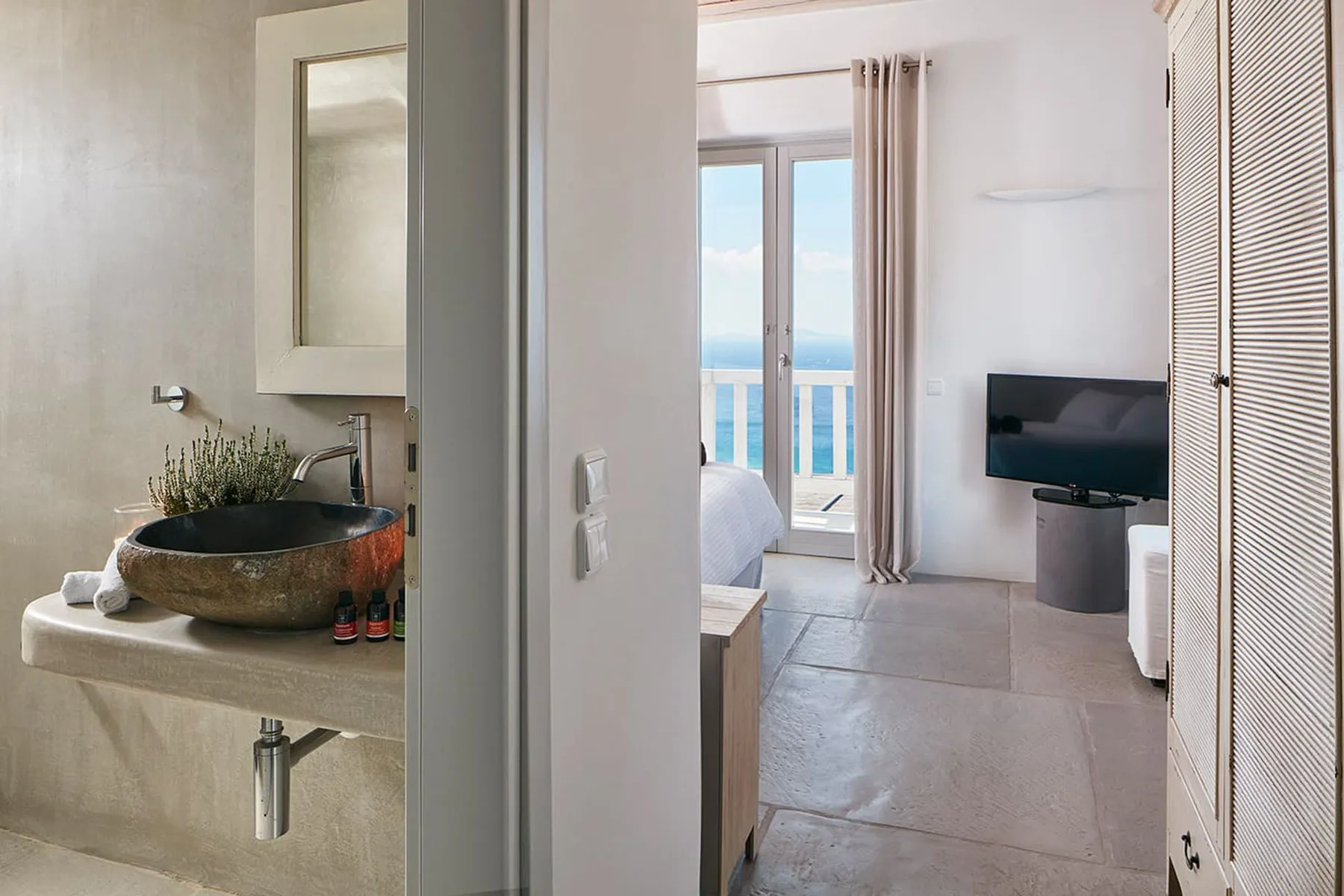 A bedroom with a television and glass doors opening onto a balcony.